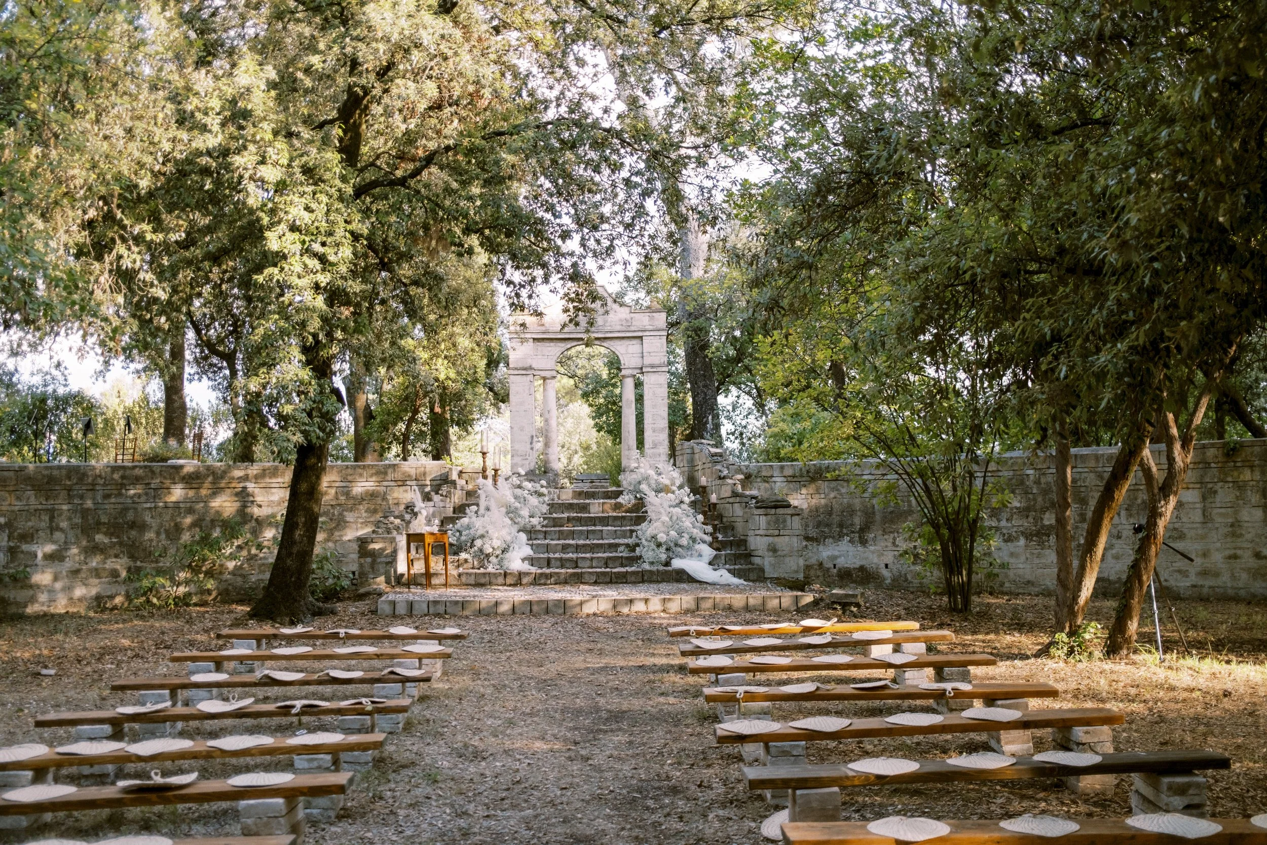 Outdoor wedding ceremony setup surrounded by historic gardens at Villa Pianciani in Umbria, Italy.