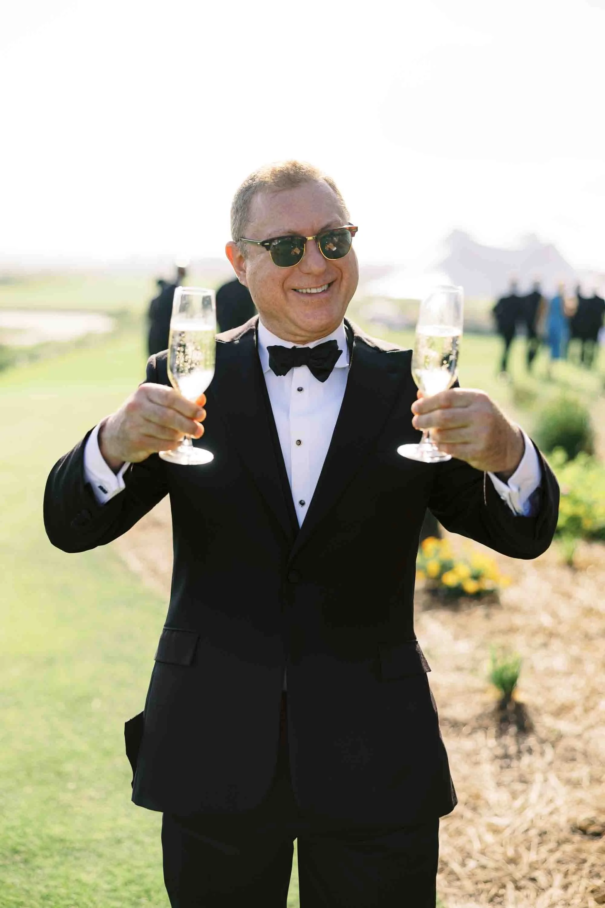 Wedding guest holding two champagne glasses and smiling during cocktail hour at a Kiawah Island wedding