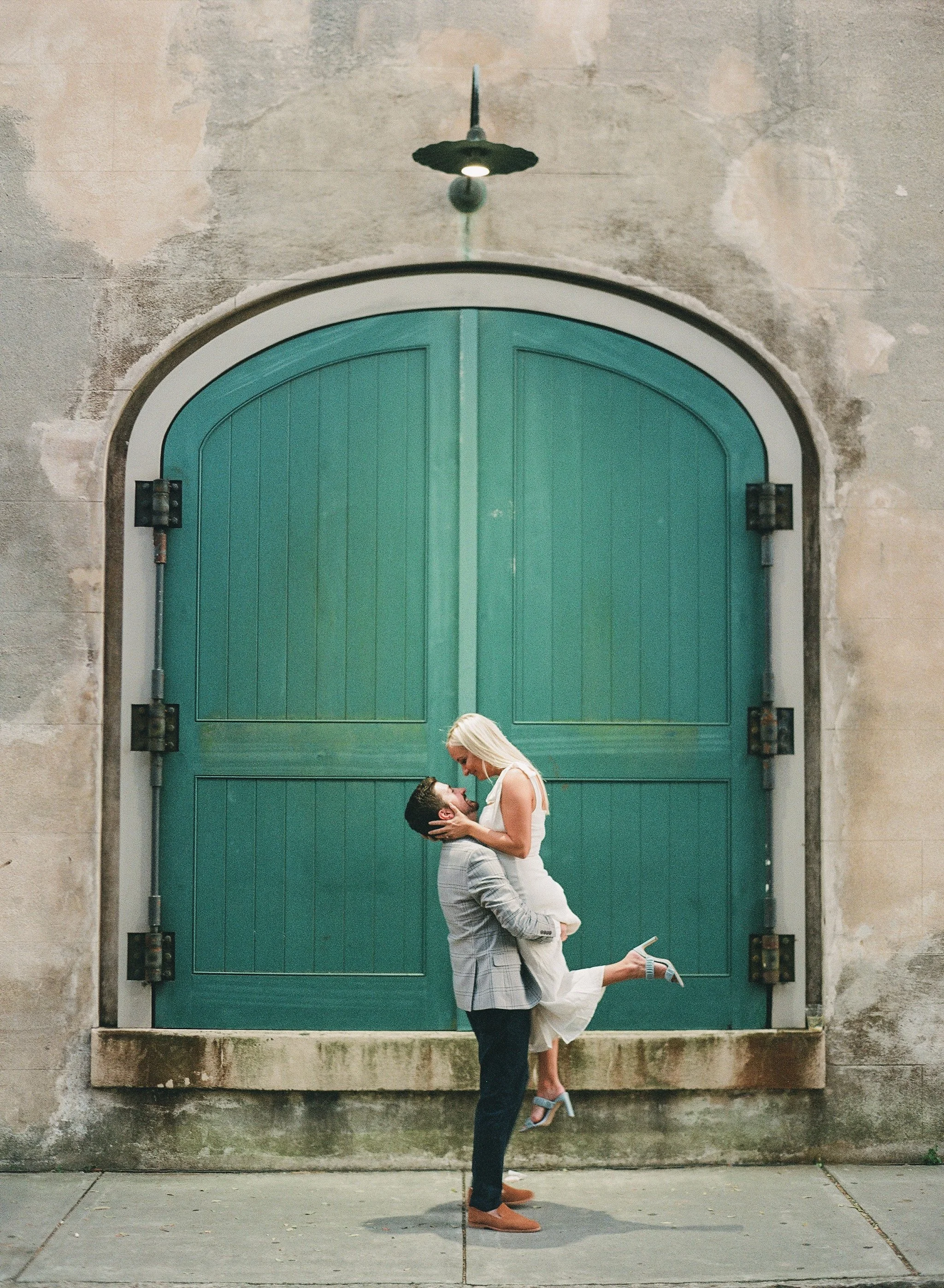full length engagement photos on Queen Street Charleston in front of arched green door