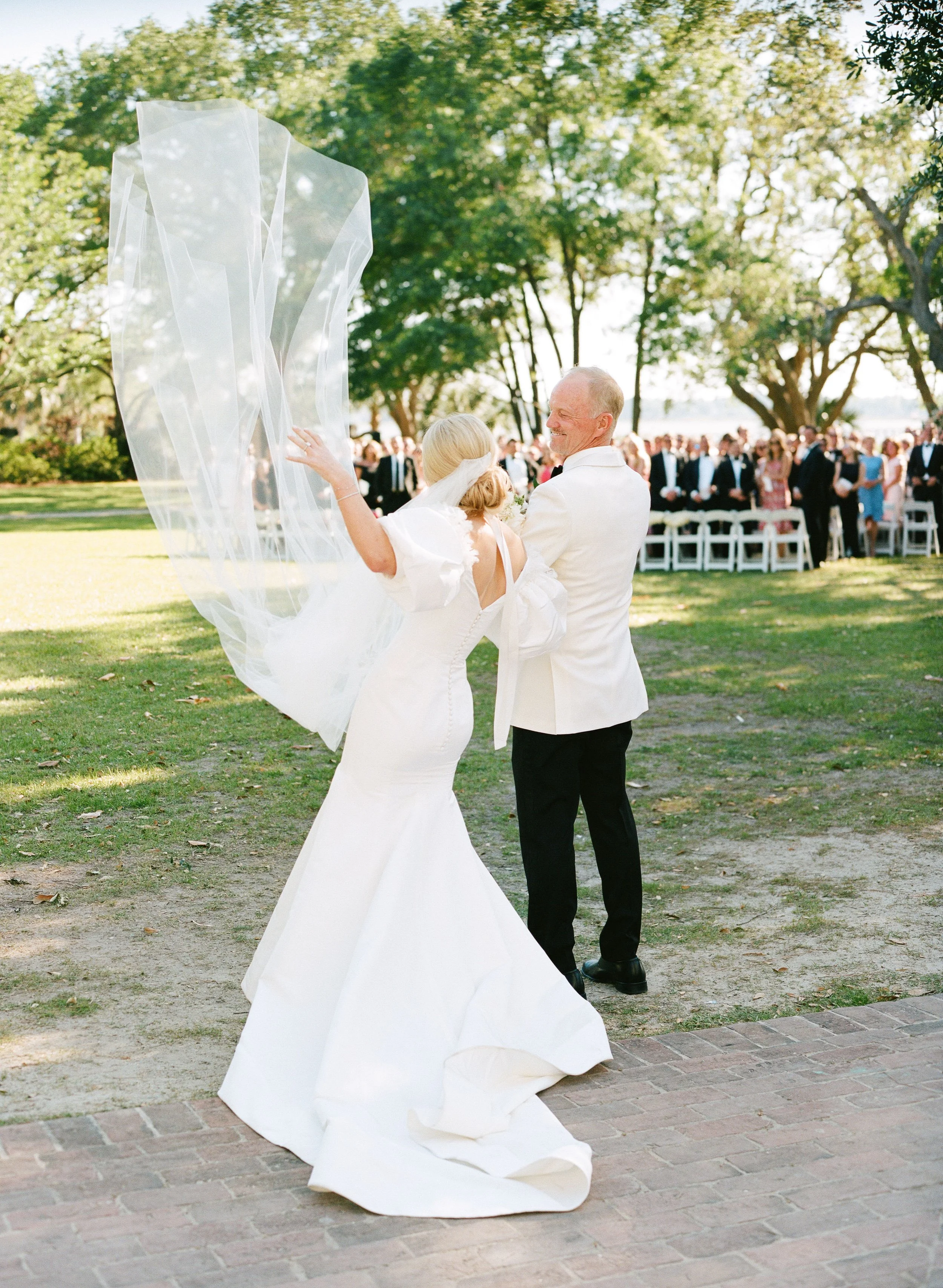 Bride’s veil lifting in the air as she walks down the aisle at Lowndes Grove in Charleston