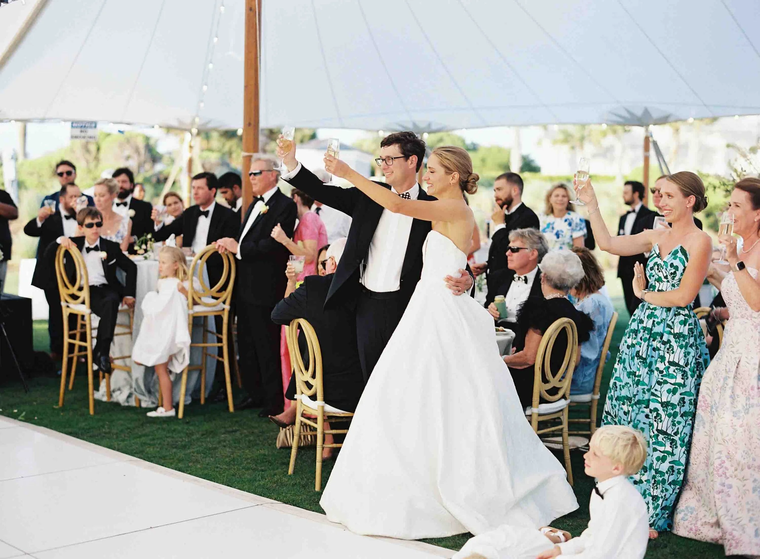 Bride and groom raising glasses during a toast at their Ocean Course wedding reception