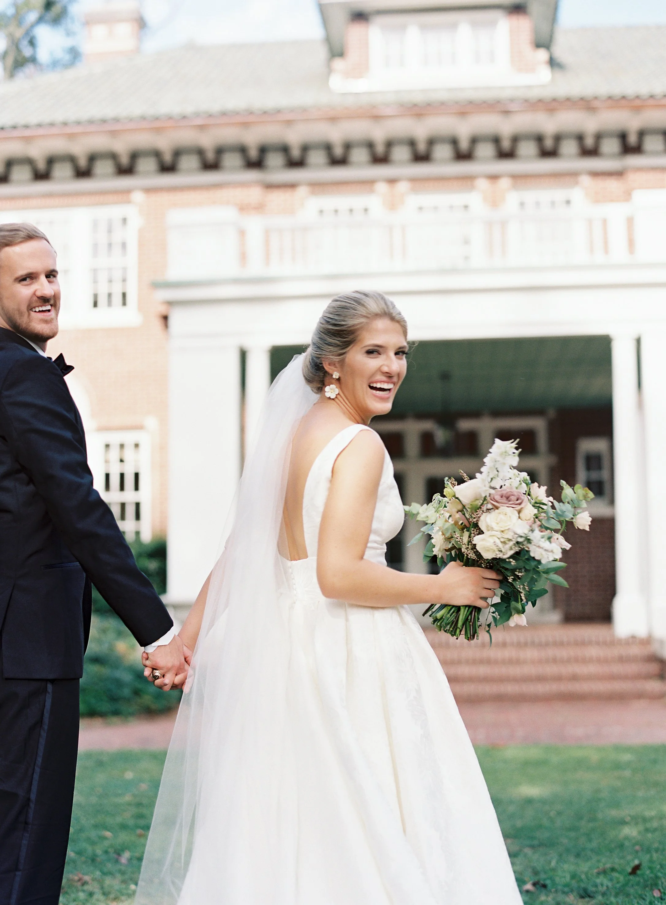 Bride and groom holding hands outside historic Stowe Mansion after wedding ceremony