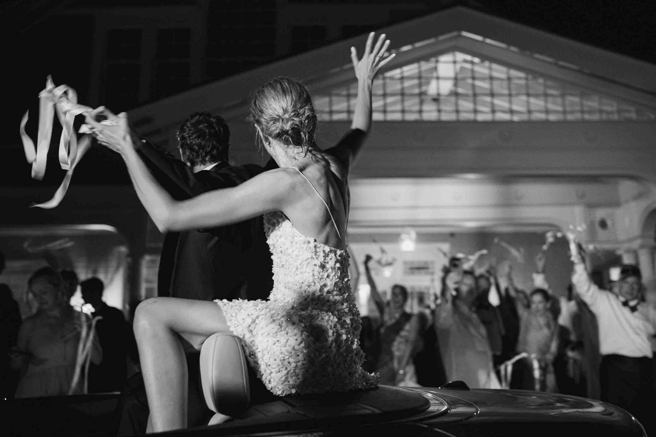 Black and white photo of bride and groom celebrating during their wedding exit at night