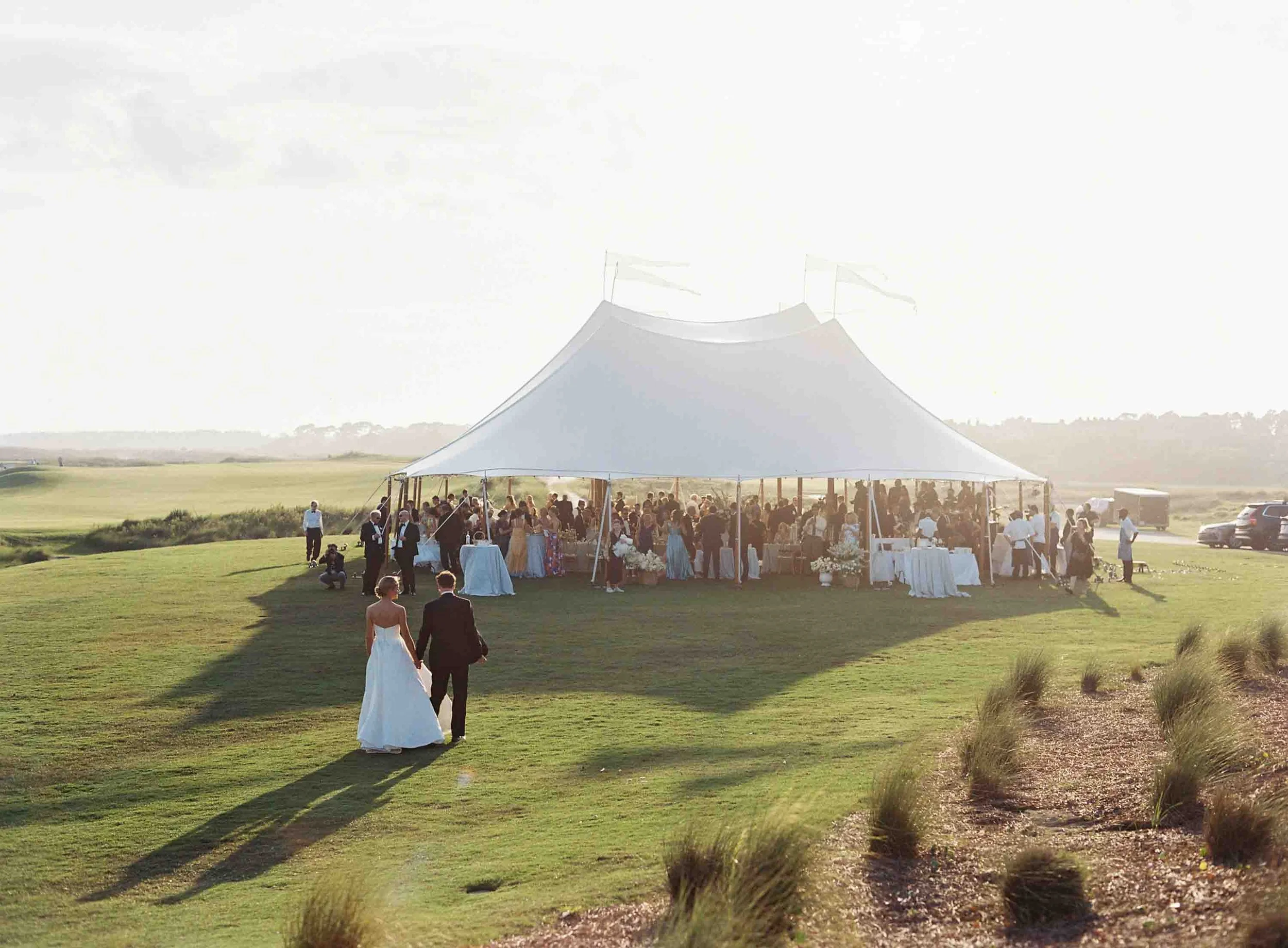 Outdoor wedding reception tent set up on the Ocean Course at Kiawah Island with guests gathering inside