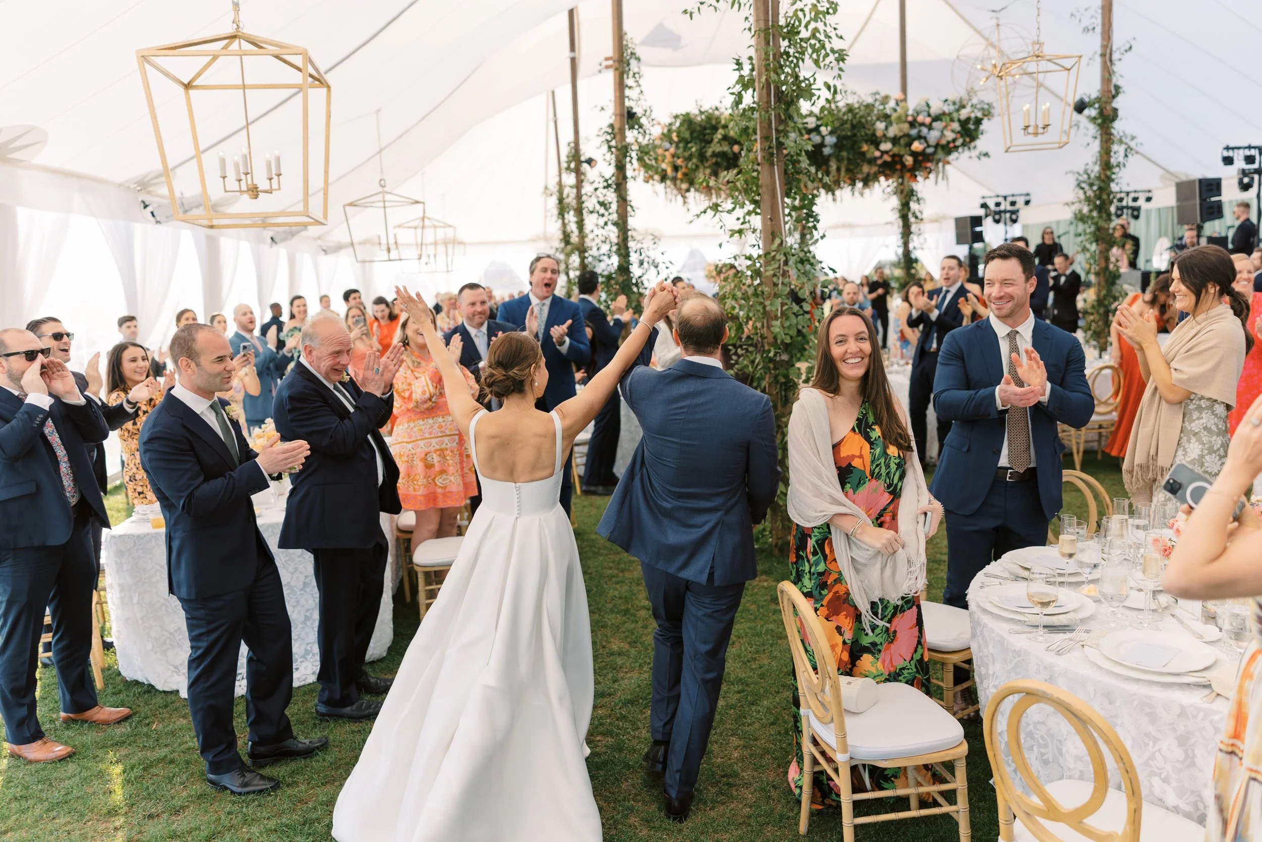 Bride and Groom kick off their wedding reception at the Ocean Course on Kiawah by celebrating under a large tent decorated with chandeliers and floral arrangements.
