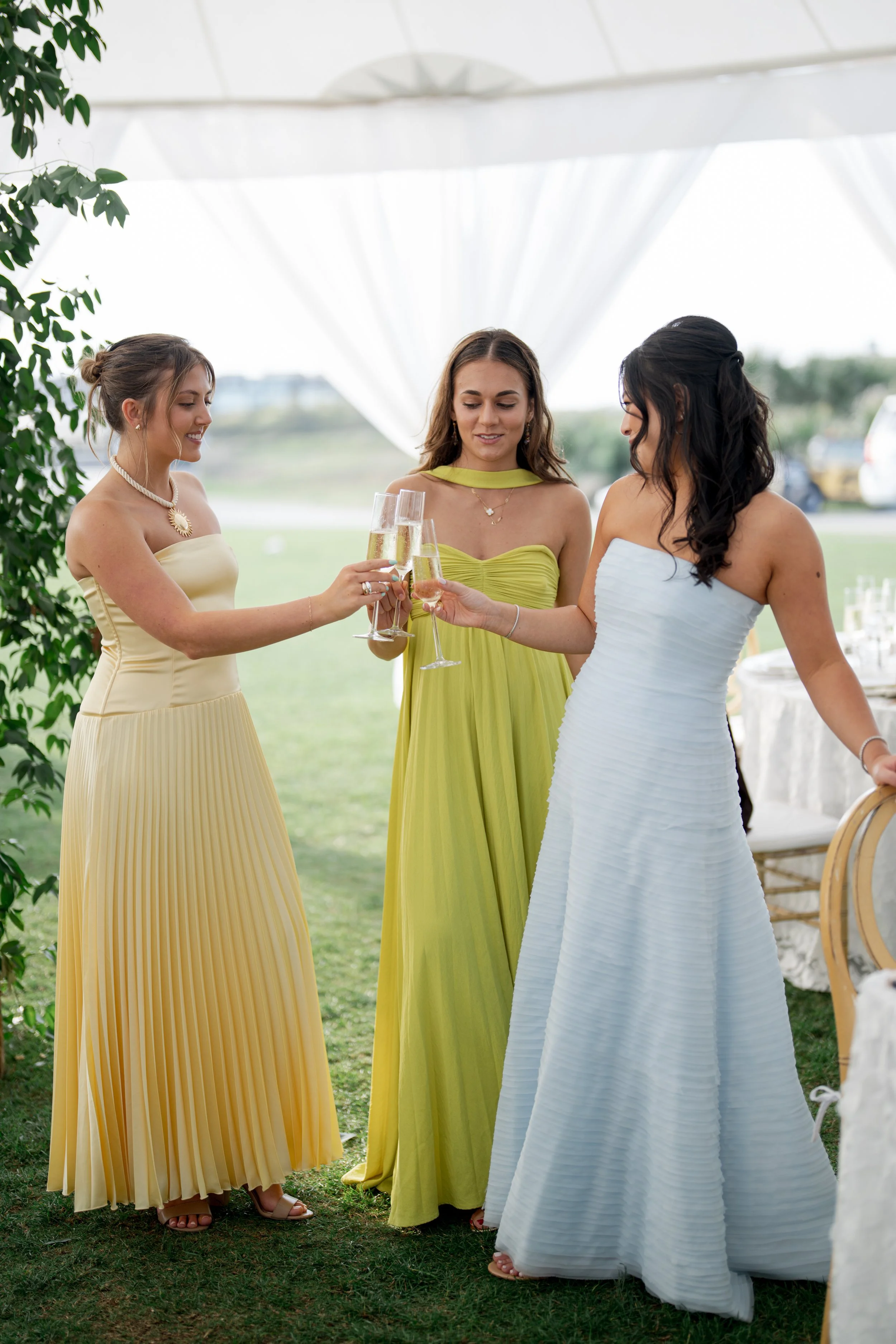 Three women in elegant dresses sharing a toast with champagne a wedding event at the Ocean Course on Kiawah Island, SC