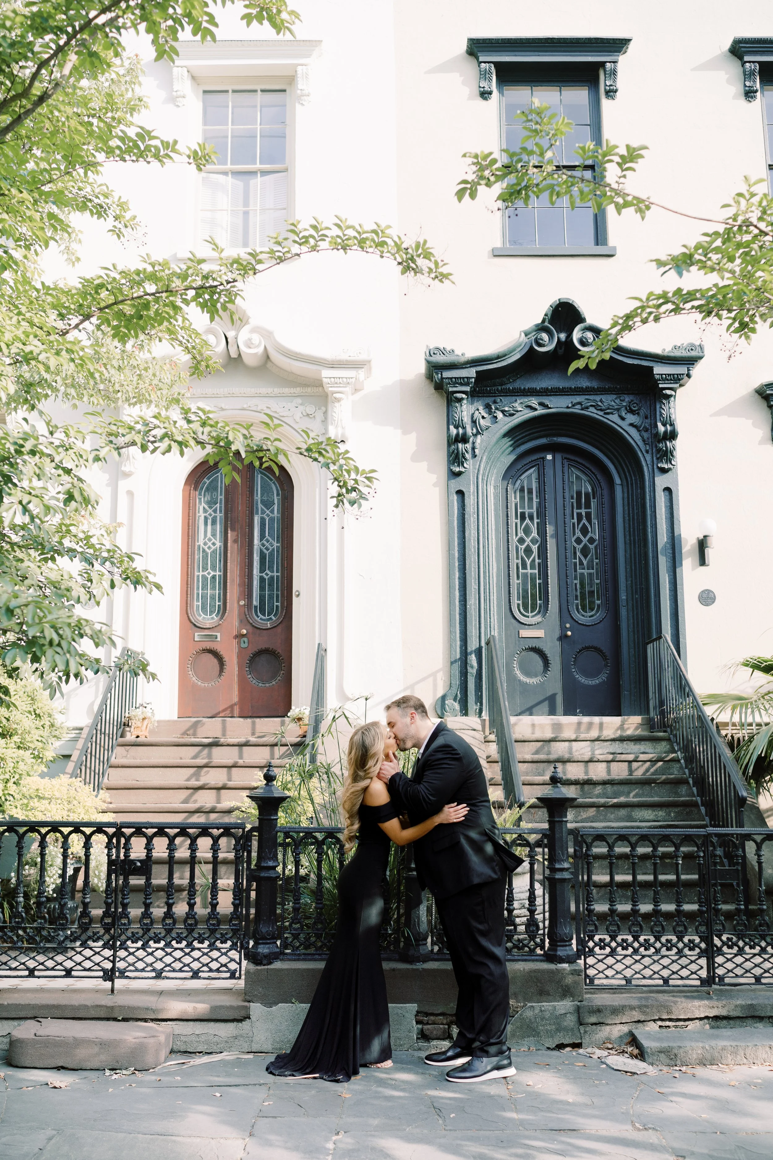 A newly engaged couple kissing during their engagement photos in downtown Charleston