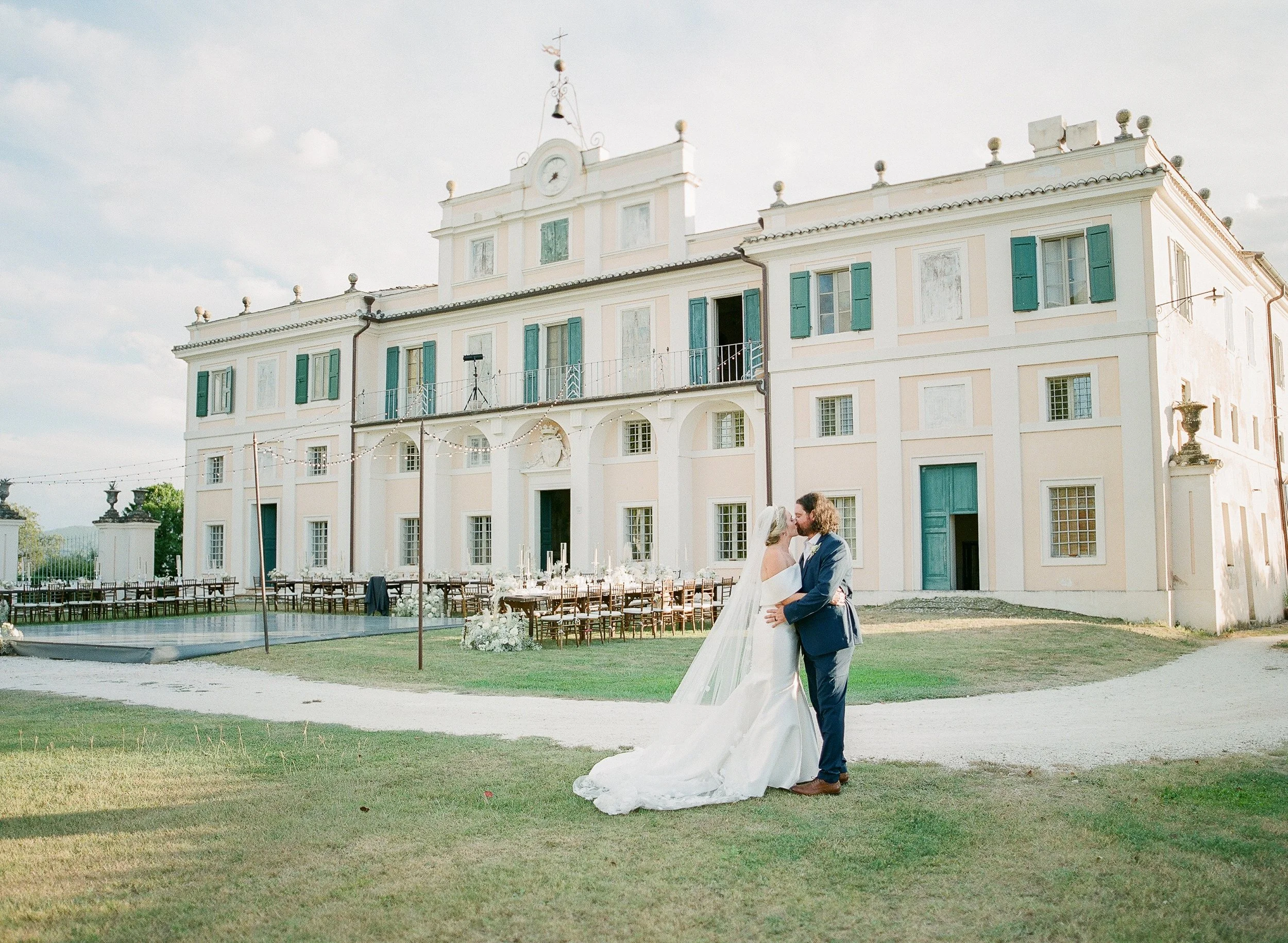 Lauren Jonas & her husband, Donnie Exelbierd, kissing on their wedding day in front of a historic villa in Italy.