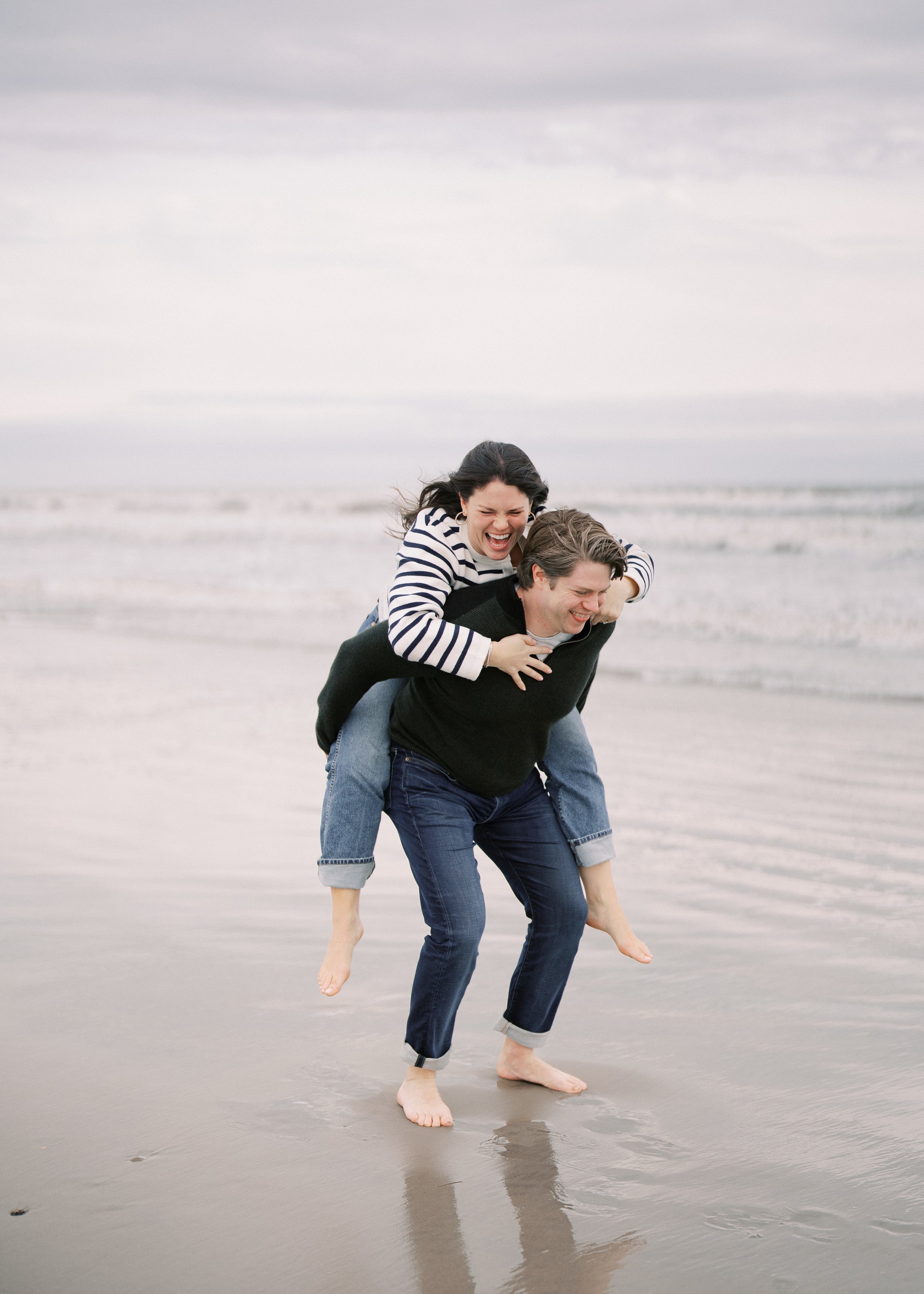 Newly engaged couple during their engagement photos on the beach at the Ocean Course
