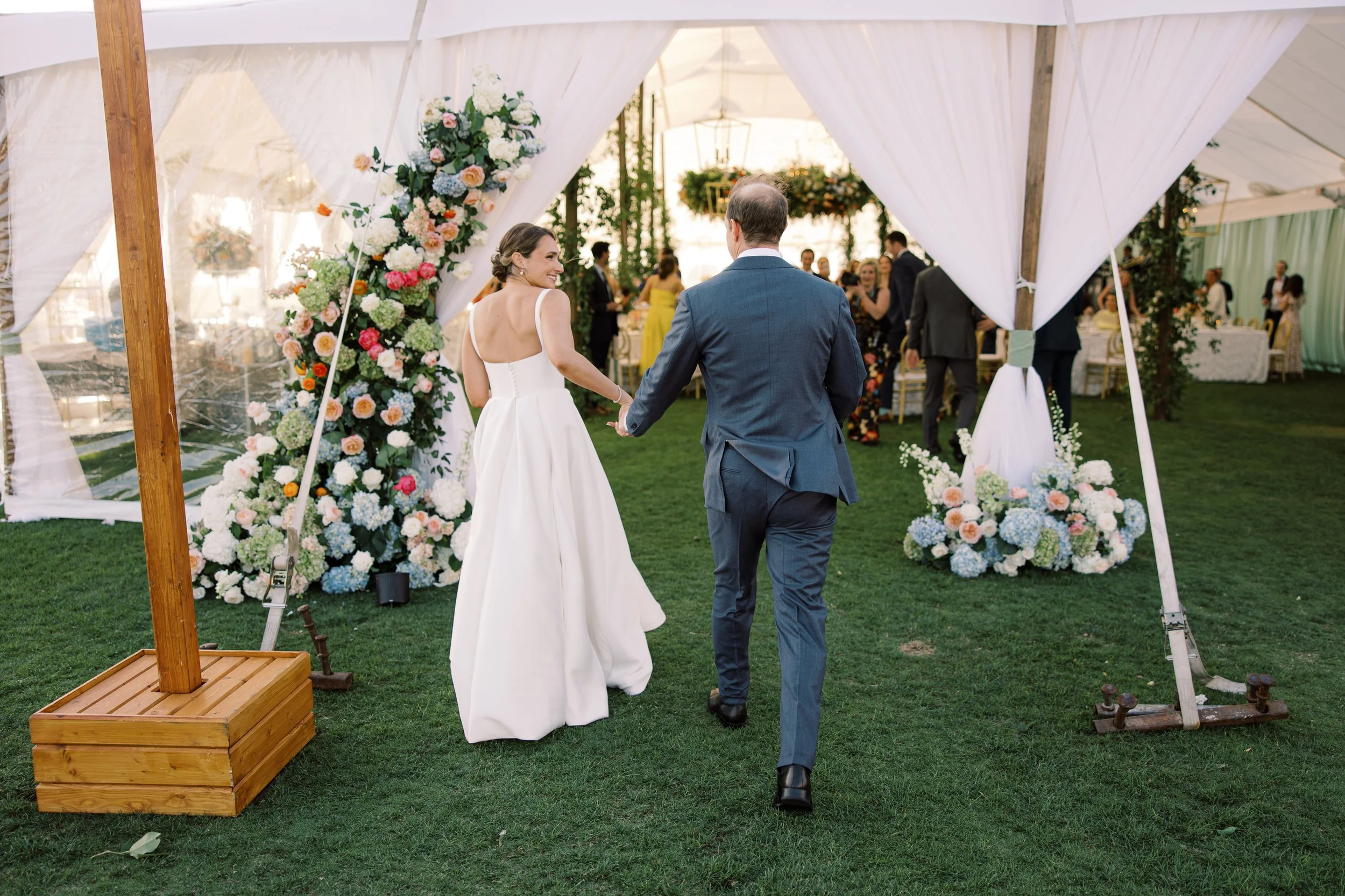 A bride and groom walking hand-in-hand into their wedding reception tent at the Ocean Course on Kiawah Island, SC