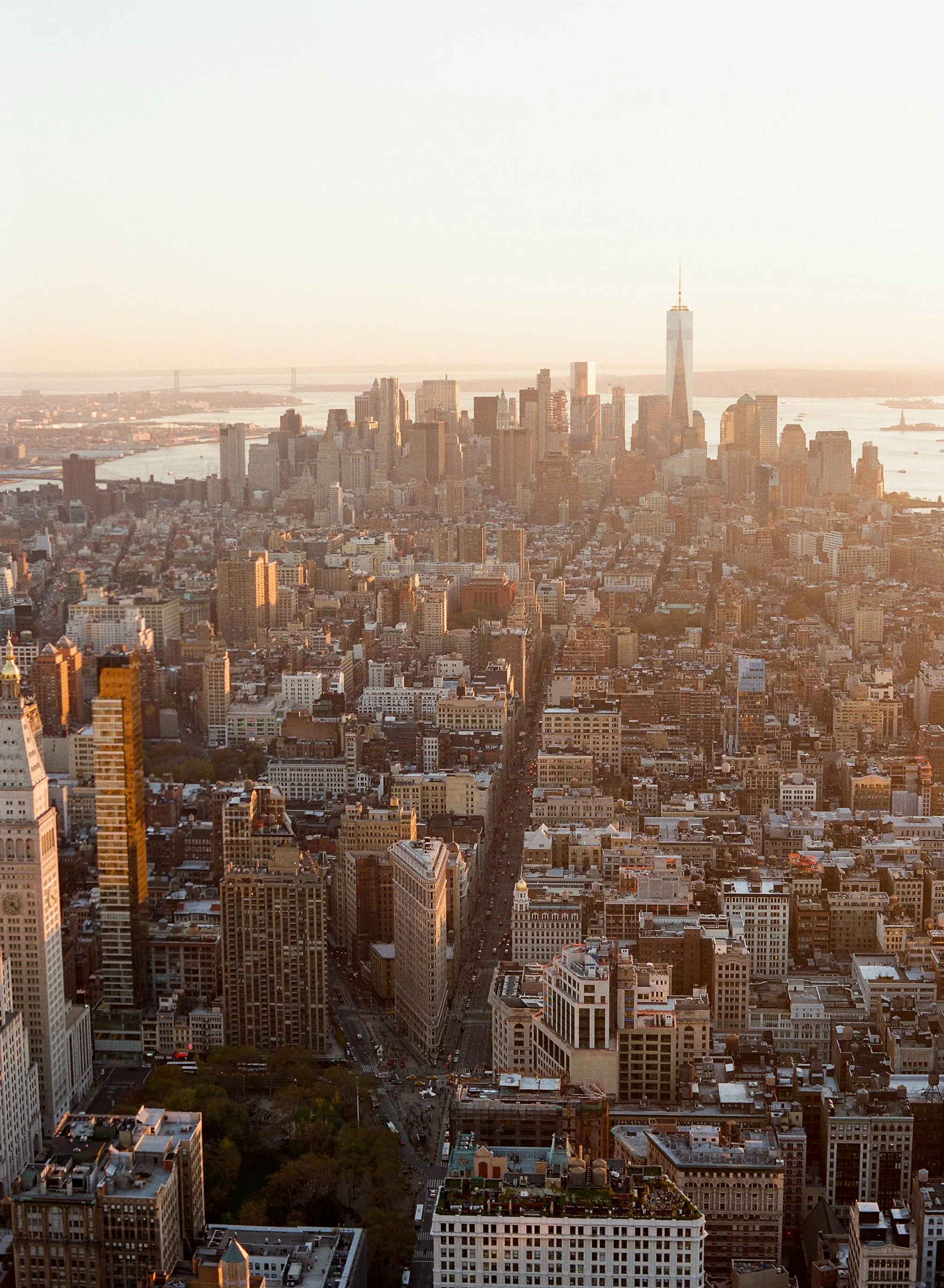 Aerial view of Manhattan skyline at sunset, showing tall buildings and streets.