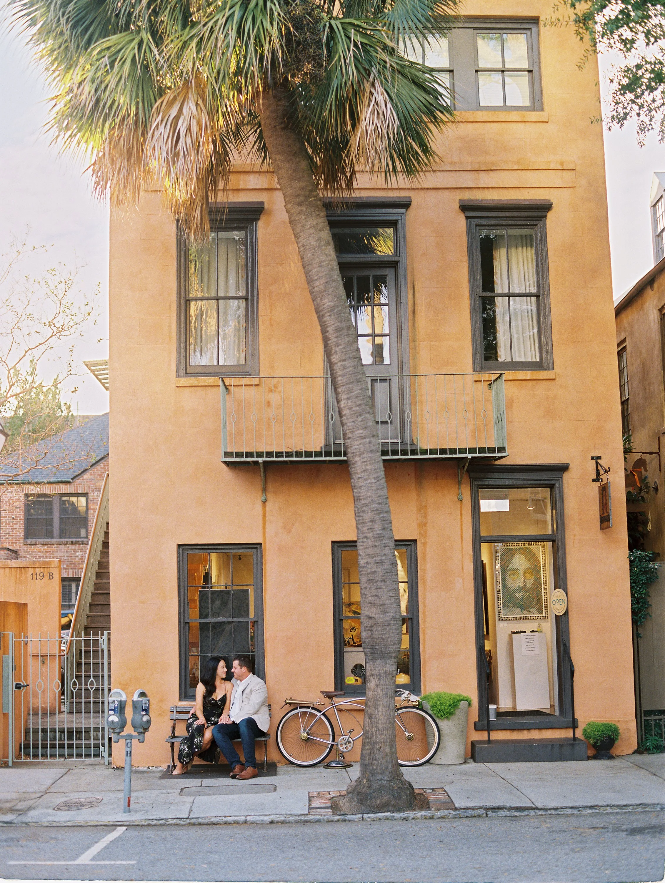 engagement photos on Church Street in Charleston with couple in front of historic home and palm tree