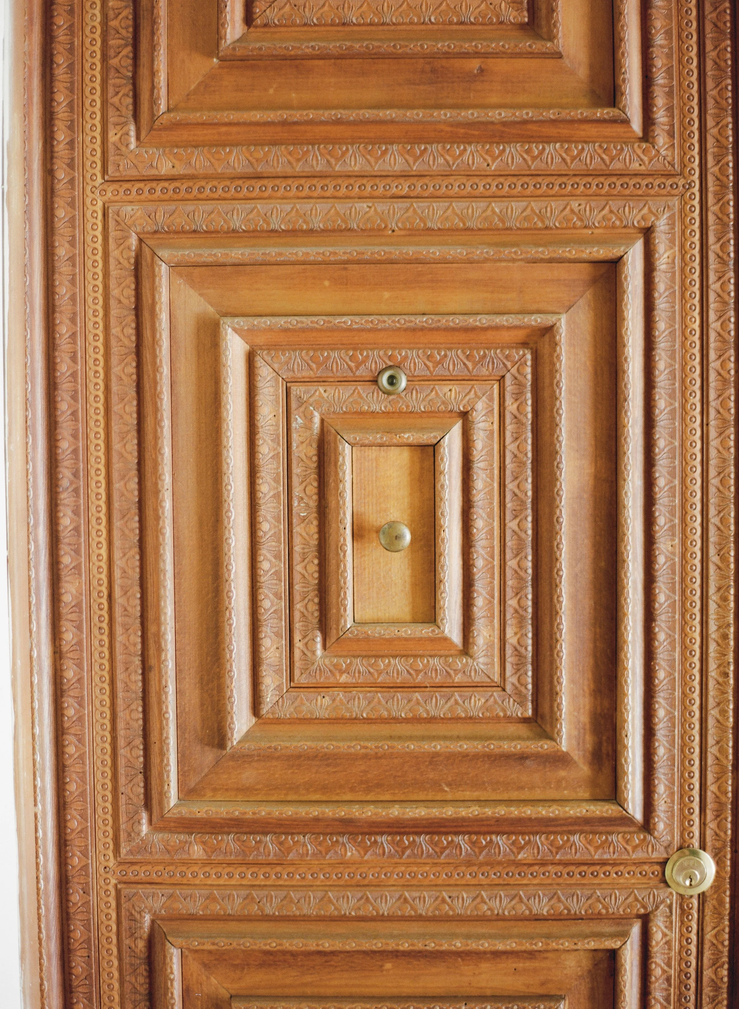 Close-up of intricately carved wooden cabinet doors in Lecce, Italy with three peep holes.