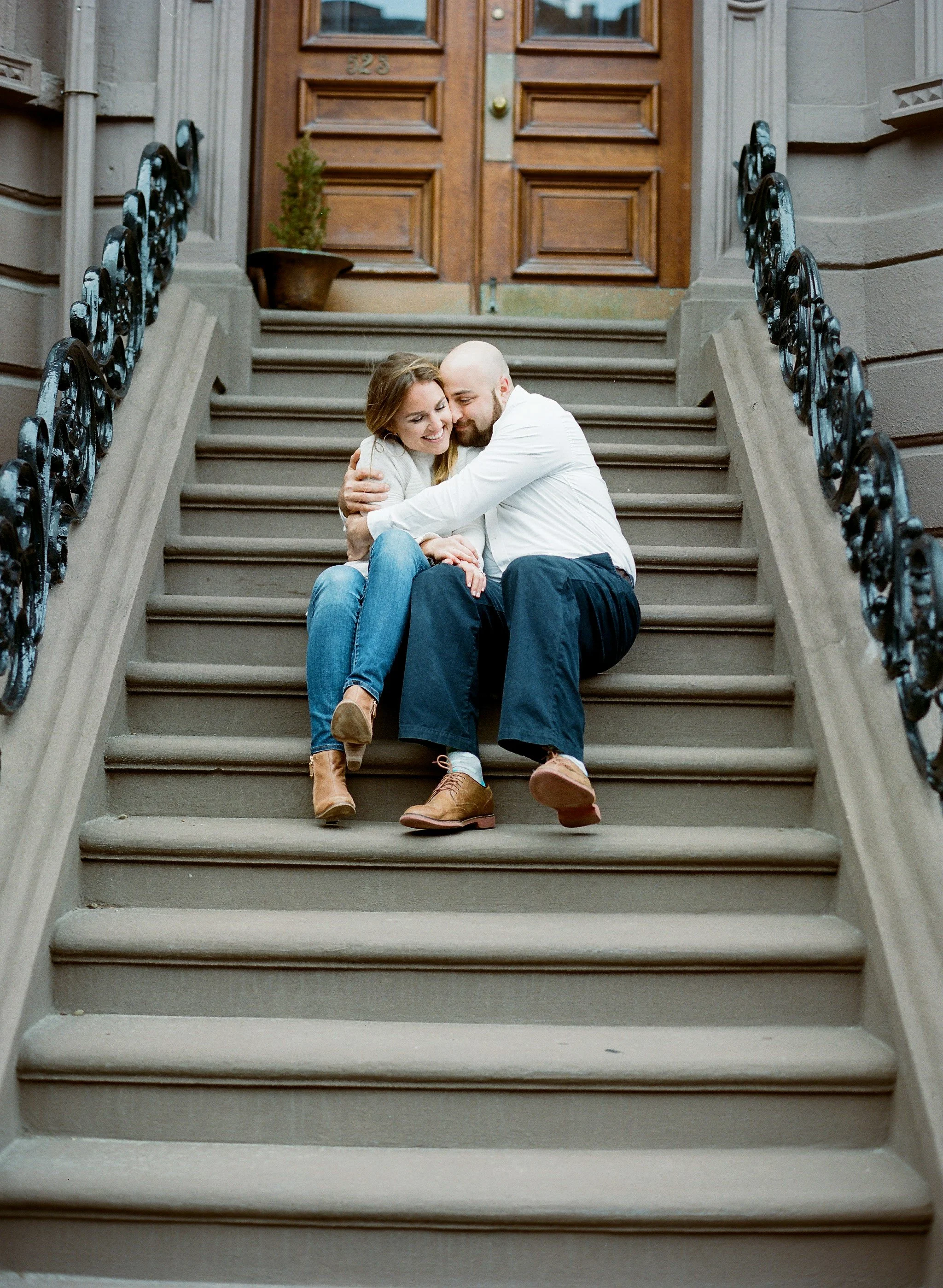 Engaged couple sitting on brownstone stairs in Boston during their engagement session