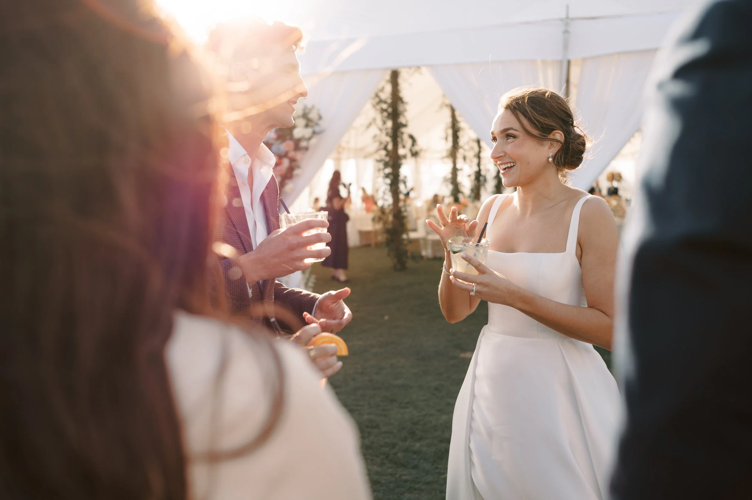 A bride in a white wedding dress smiling while talking to guests at her outdoor wedding reception at the Ocean Course on Kiawah Island, SC