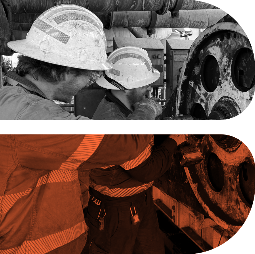 Workers in hard hats inspecting large machinery in an industrial setting.