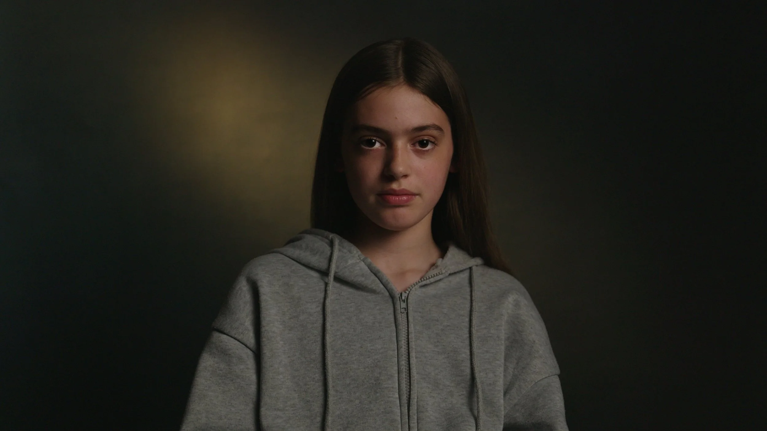 A girl looks into camera in-front a dark backdrop, It's Not Just Banter