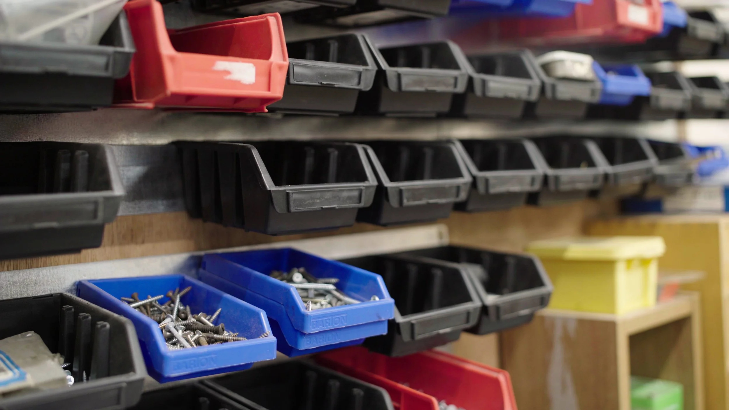 A row of small baskets, each holding miscellaneous objects for working with wood (nails etc), Men's Shed 