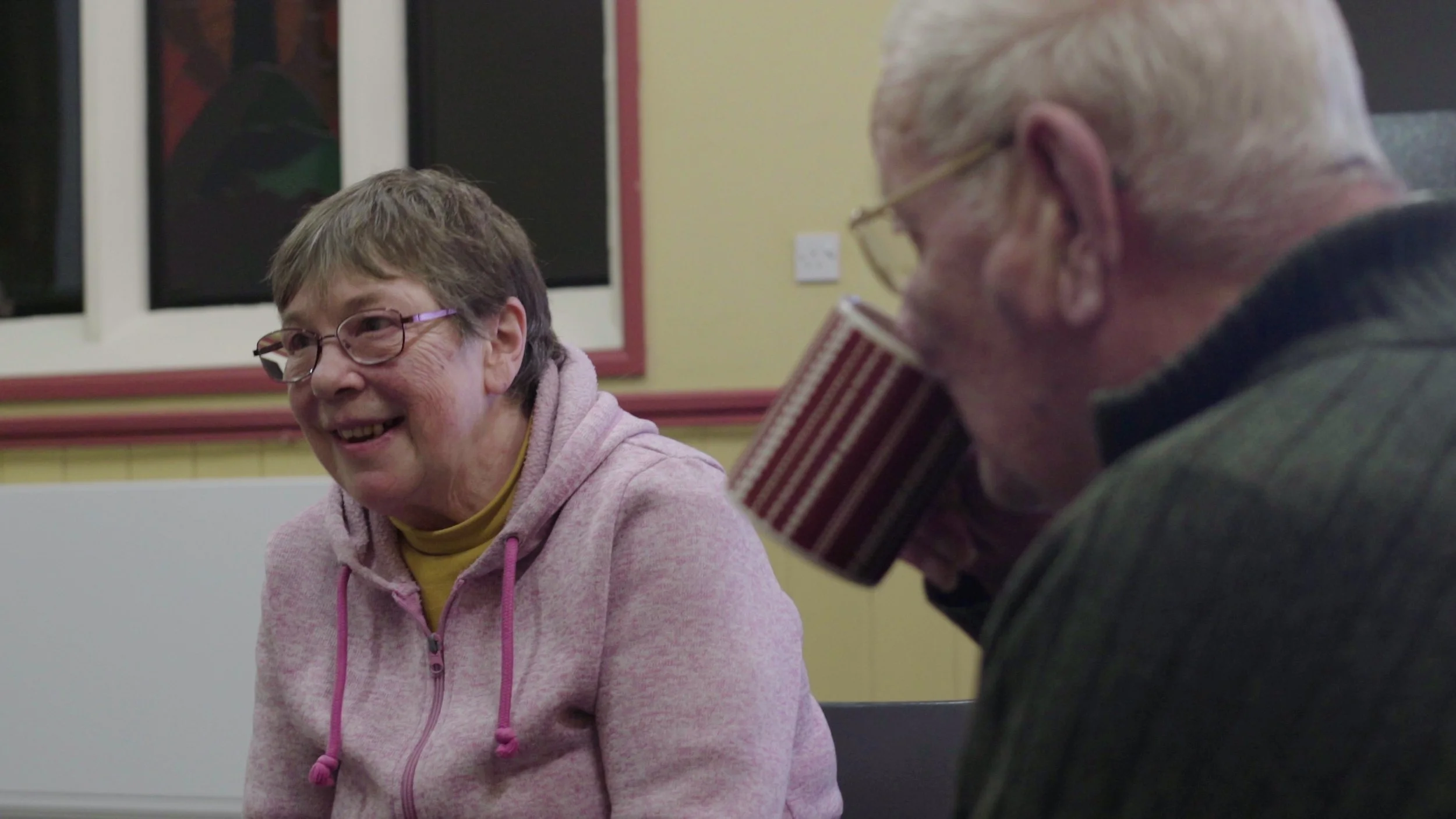 A woman speaks as a man drinks from a mug, Warwick Bereavement Group