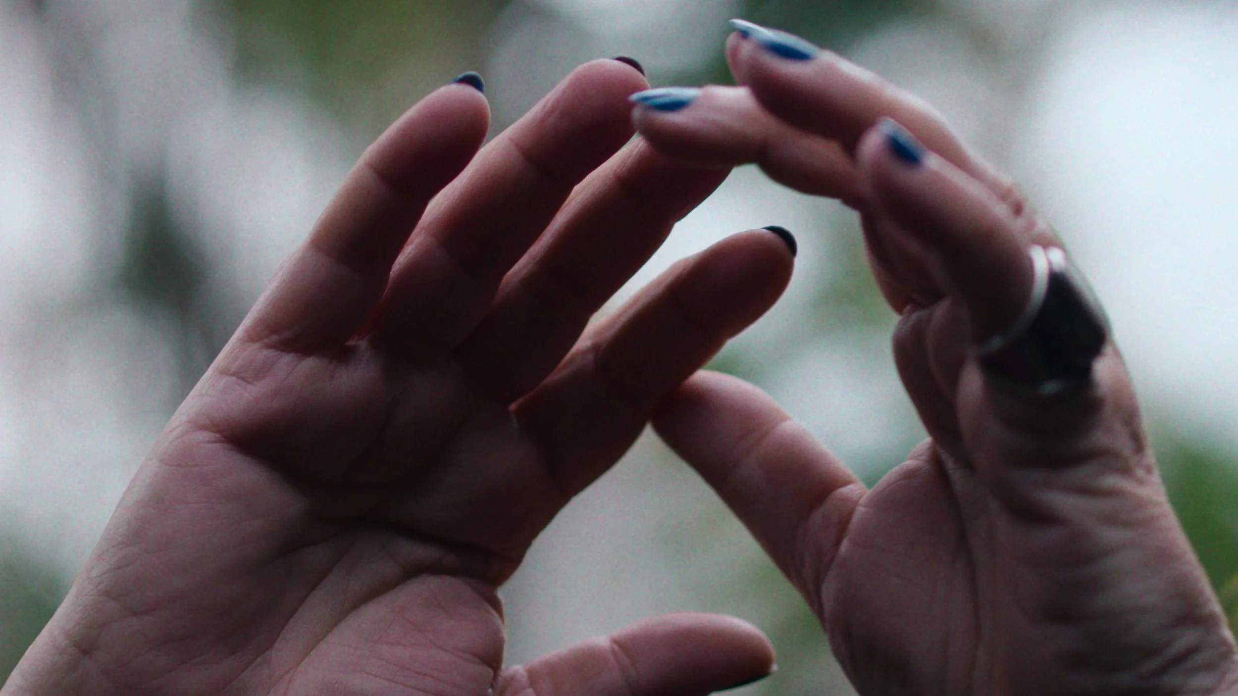 A woman holds her hands in the air against green leaves in the Barbican Conservatory, GRETA