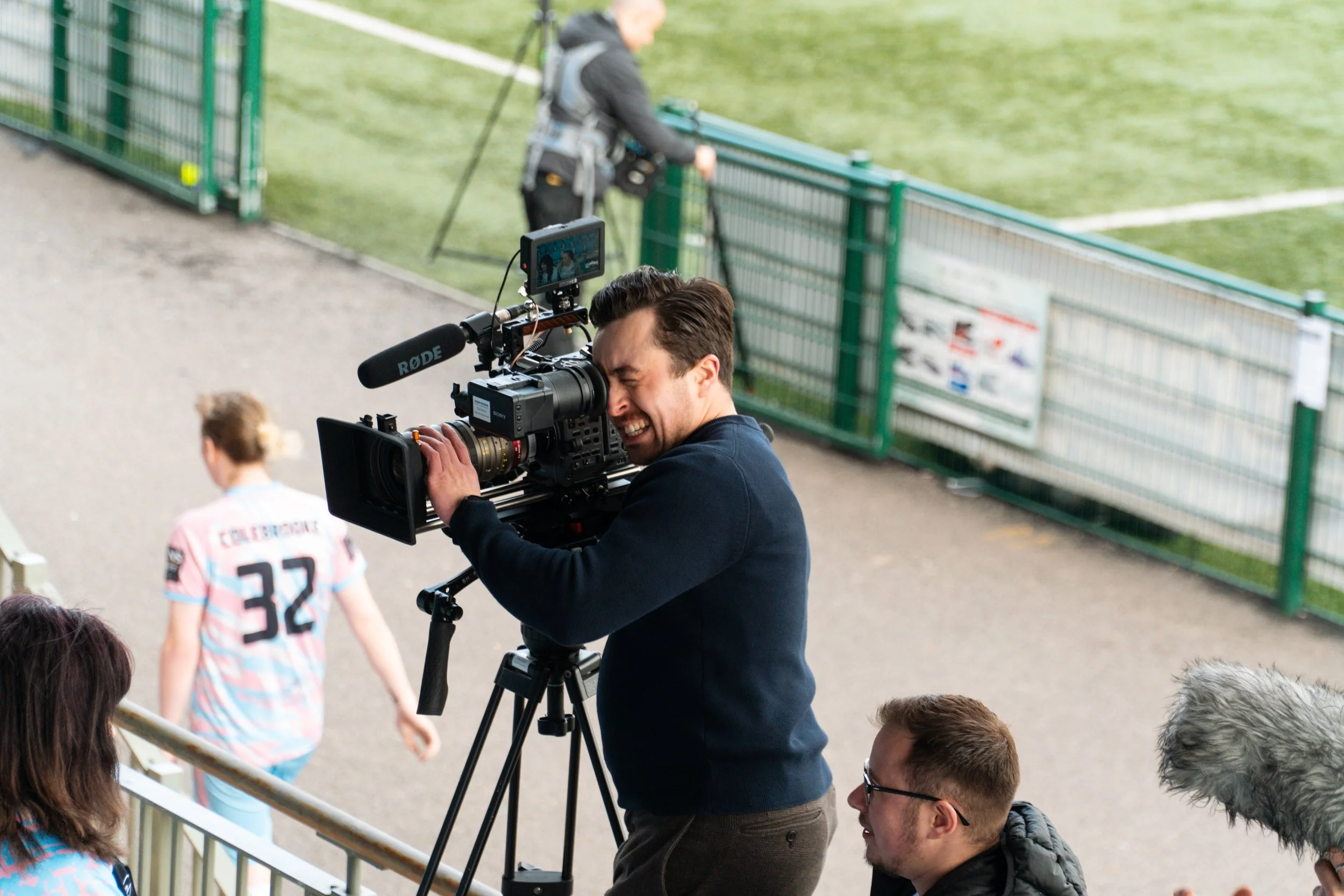 Adam Hudson lines up a shot with his camera on a tripod on the set of We'll Go Down in History