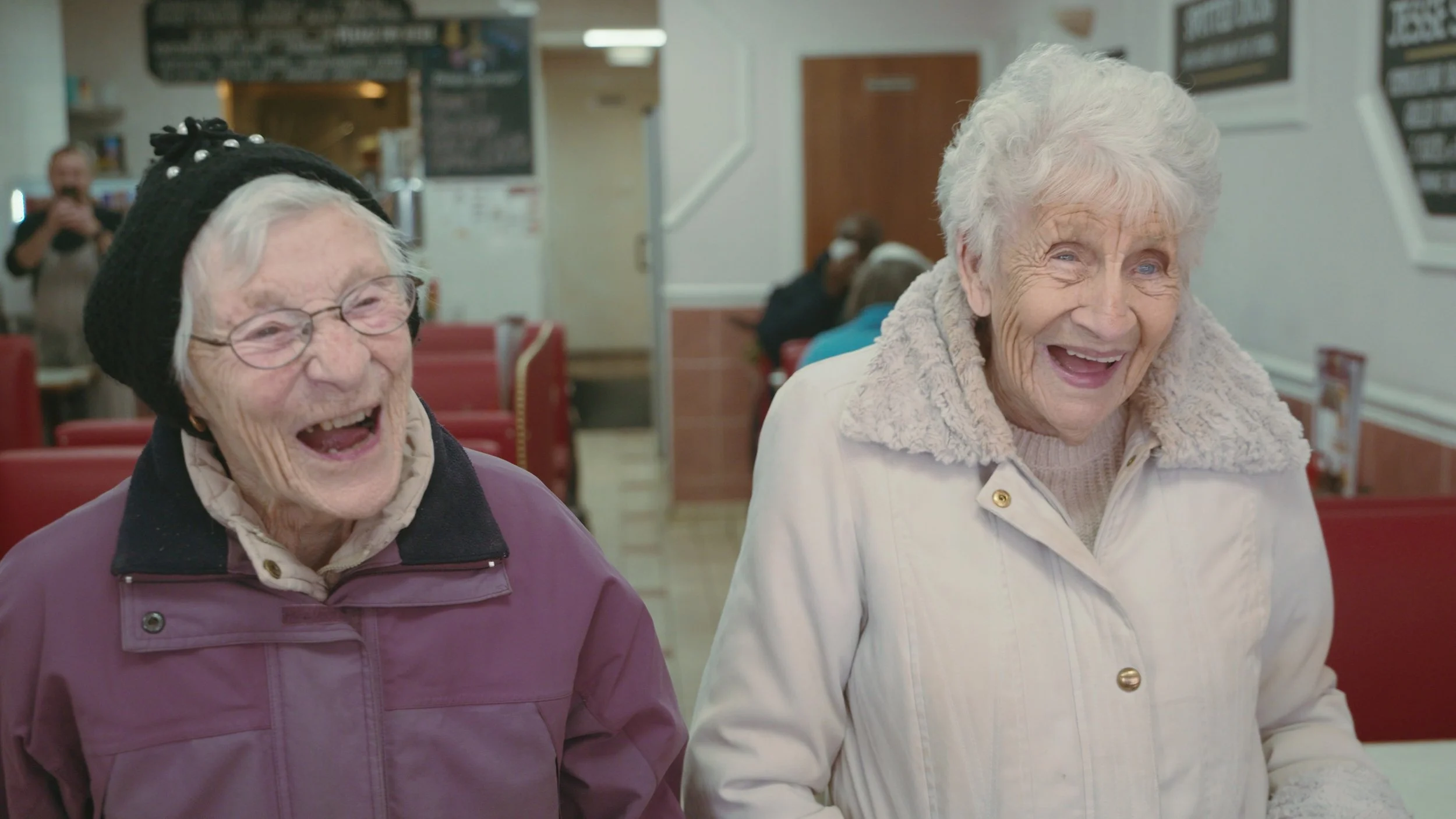 Two elderly women laugh at a joke in a old-school London café, King Dick