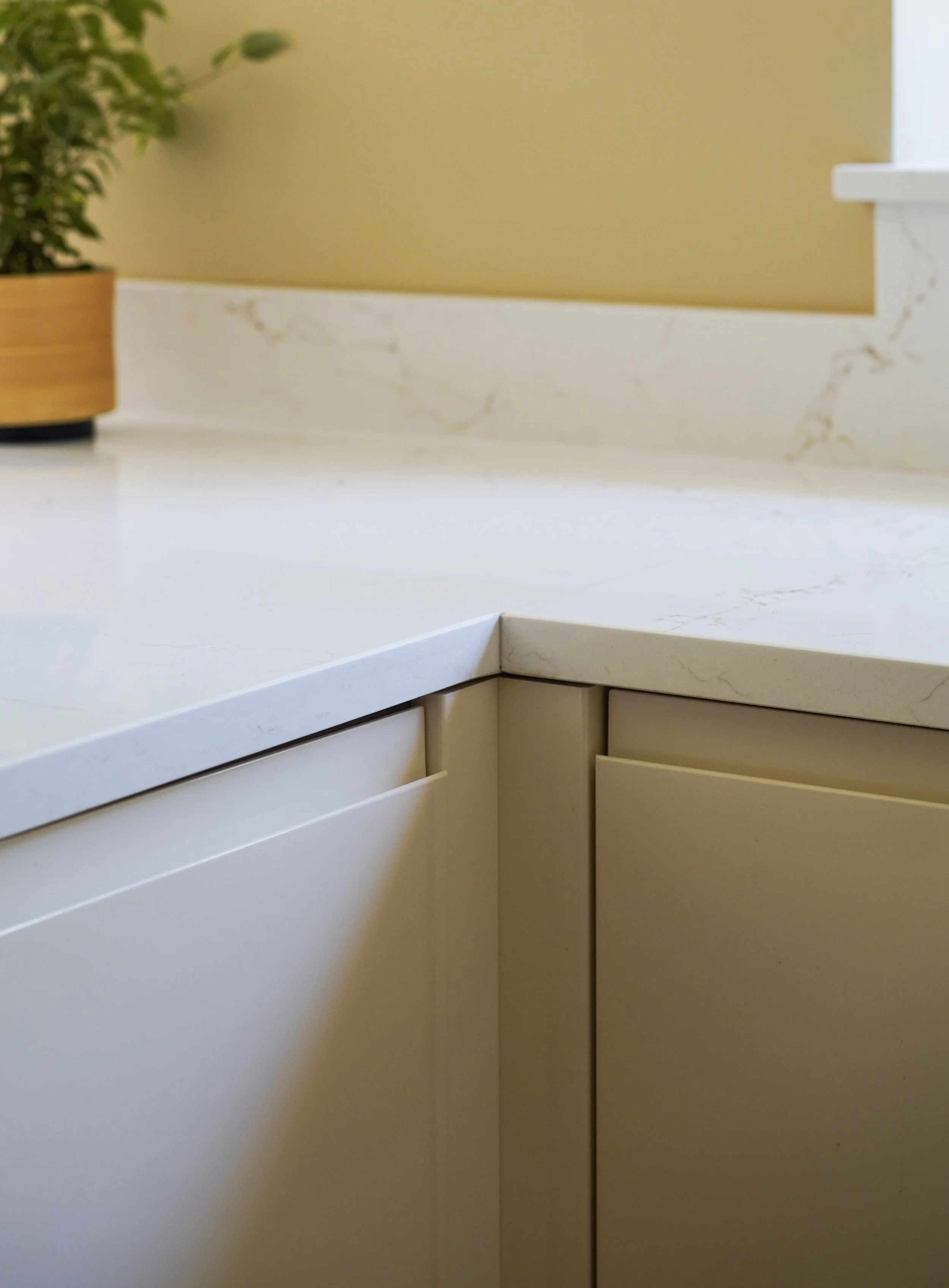 White quartz worktop and upstand meeting cream gloss kitchen units