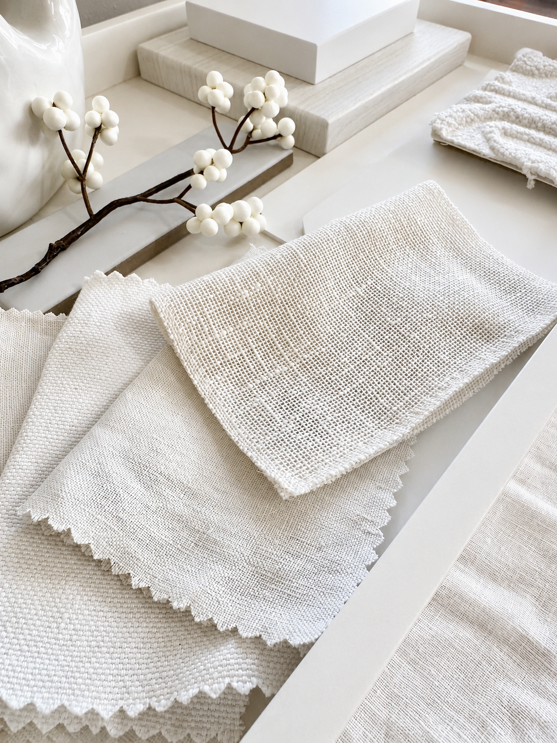 Layered linen and boucle fabric swatches in soft shades of white