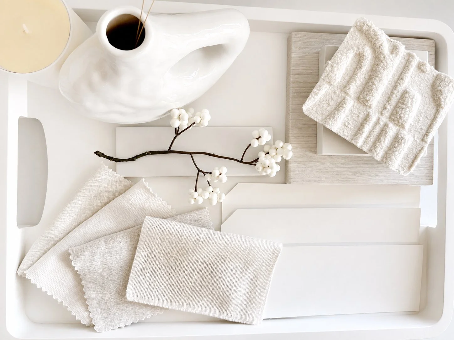 Shades of White Interior design swatches on a tray, showing boucle, linen, marble and pale wood textures for a white room scheme