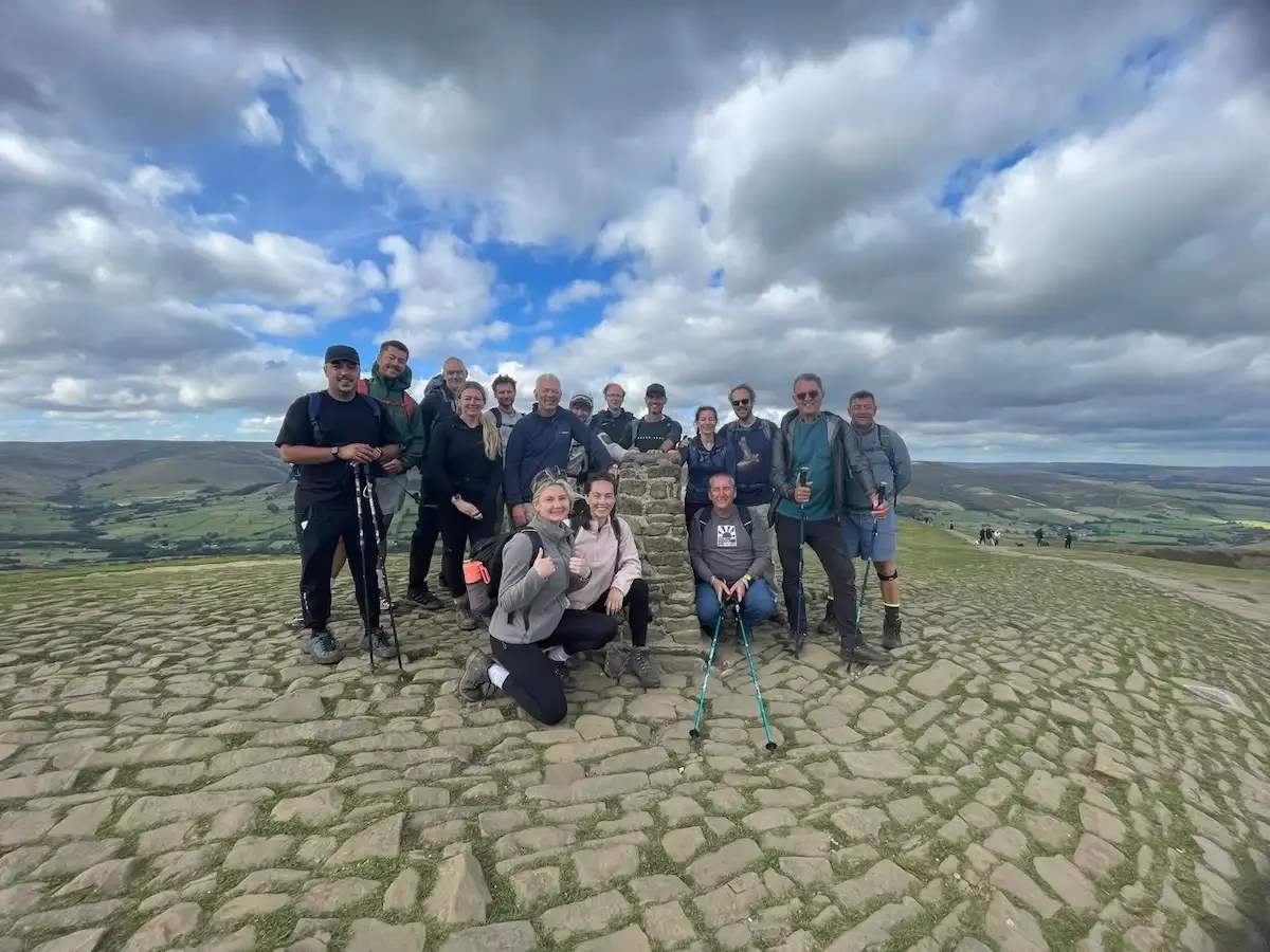 A large group of people stood on the top of a mountain in the peak district.