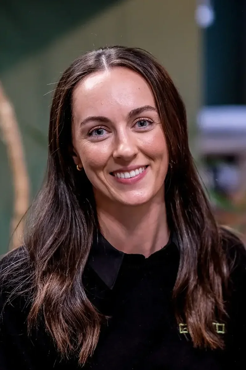 A young women with dark wavy hair smiling for a headshot