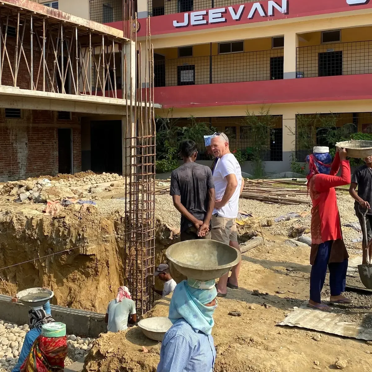 Two men stood in front of a building in Nepal called 'JEEVAN'.