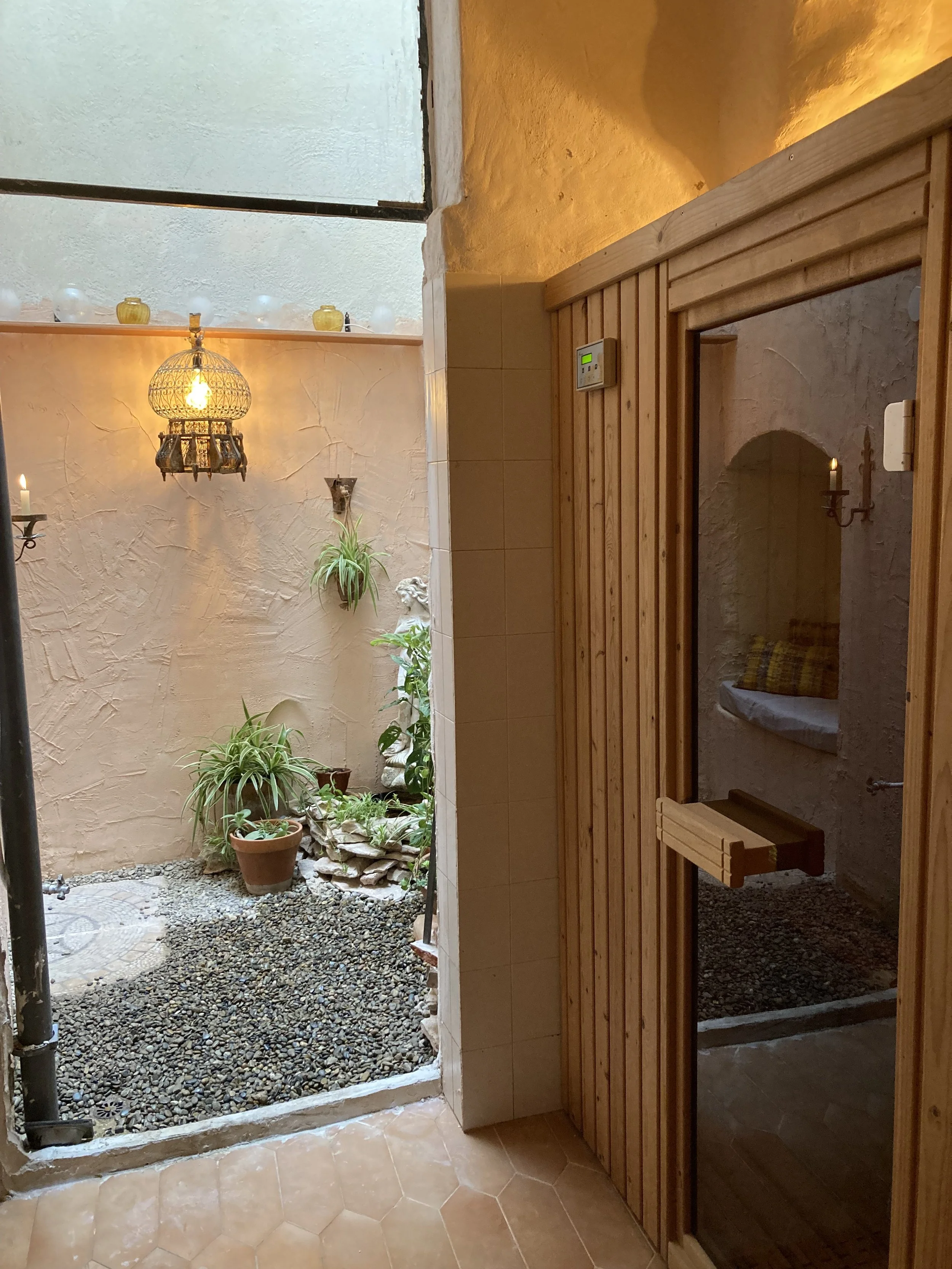 Indoor courtyard with a wooden sauna, potted plants, and ambient lighting.