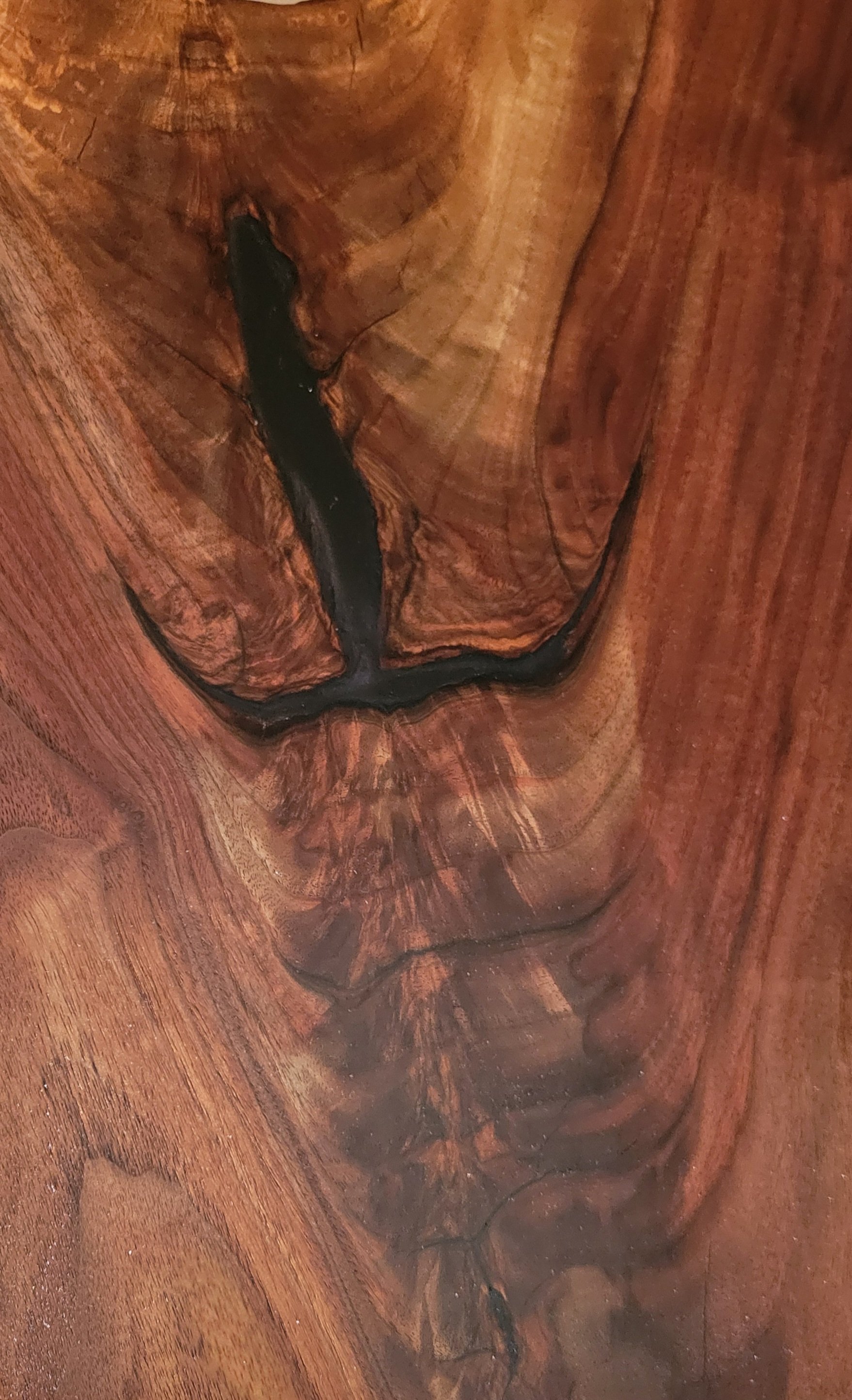 Close-up of polished wood surface with natural grain and a dark streak running through the center.
