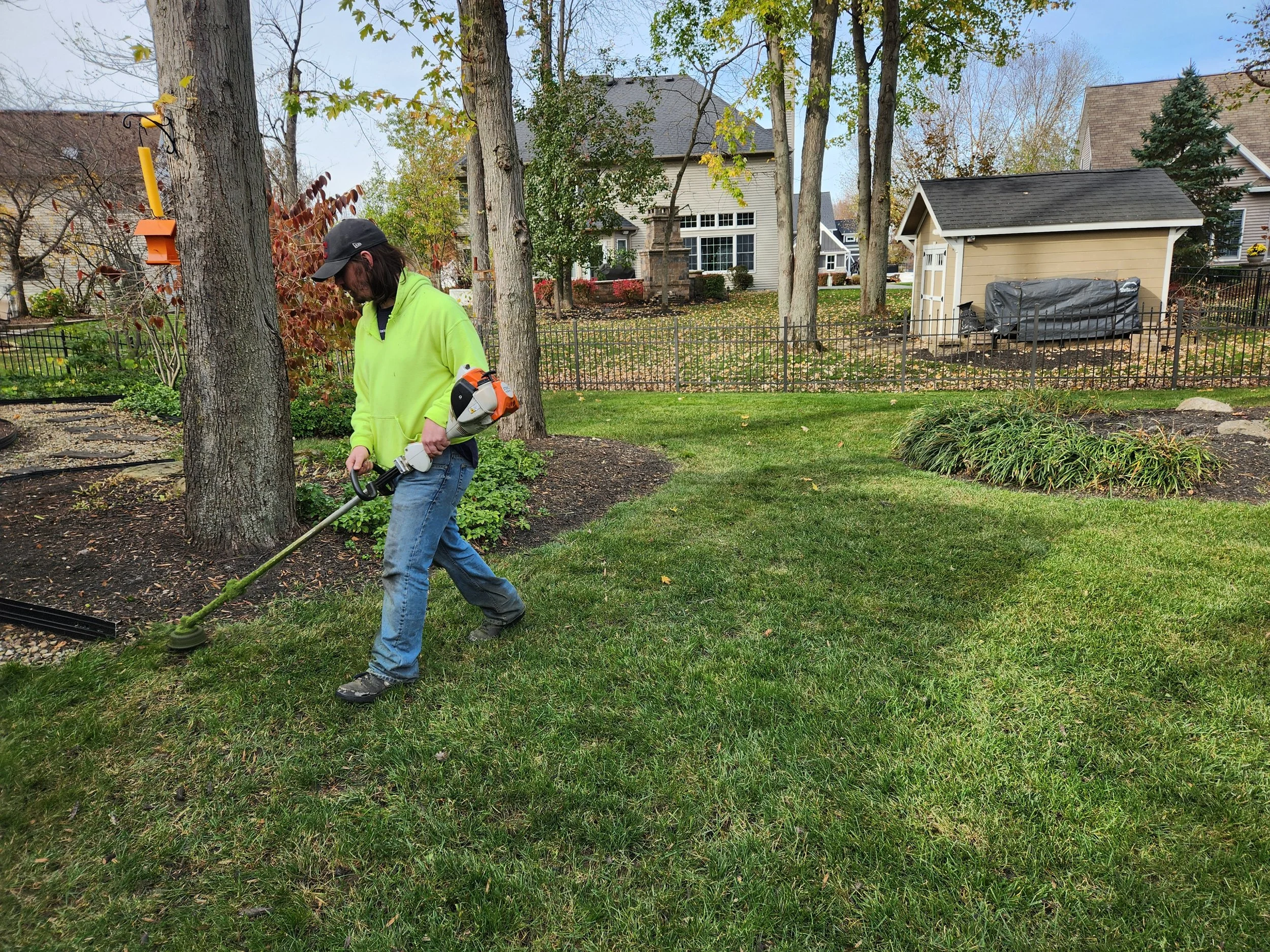 King Cut crew string trimming a residential lawn and landscape bed