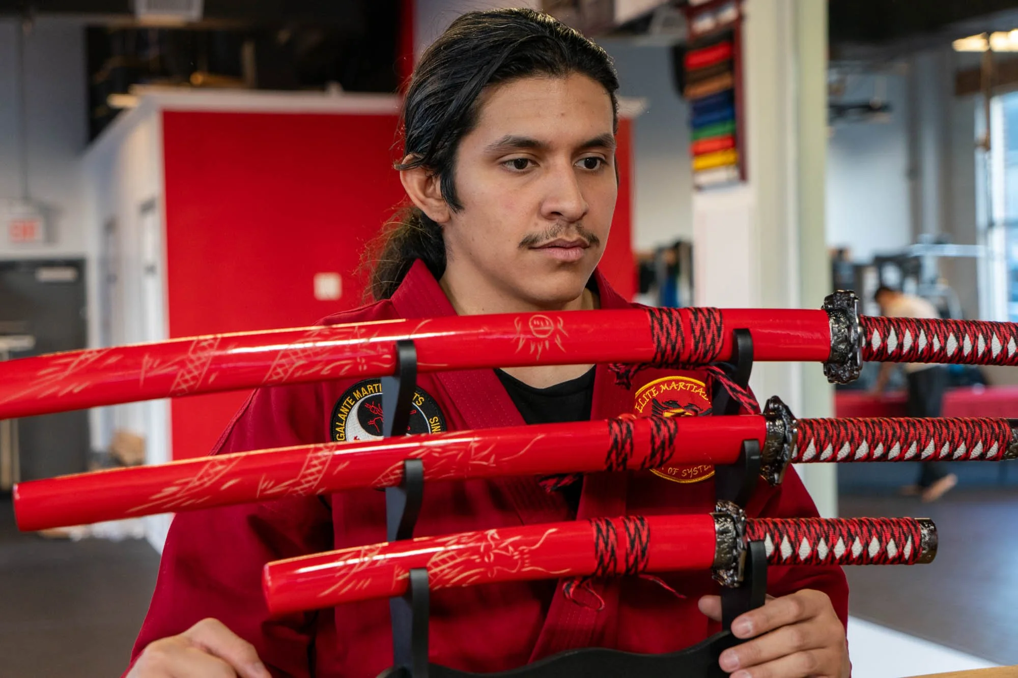 A woman practicing martial arts in a gym, wearing boxing gloves, performing a high kick.