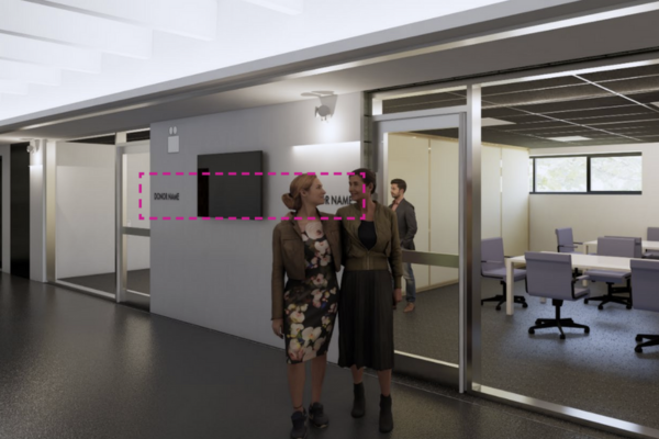 Two women standing outside a classroom with Donor Name printed on the wall
