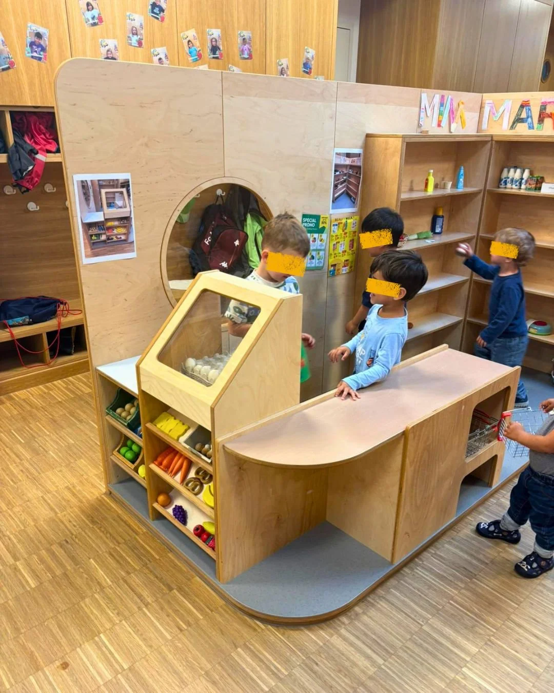 Enfants jouant à la marchande dans l'espace d'imitation en bois Mini Market de notre crèche à Leudelange pour stimuler la socialisation.