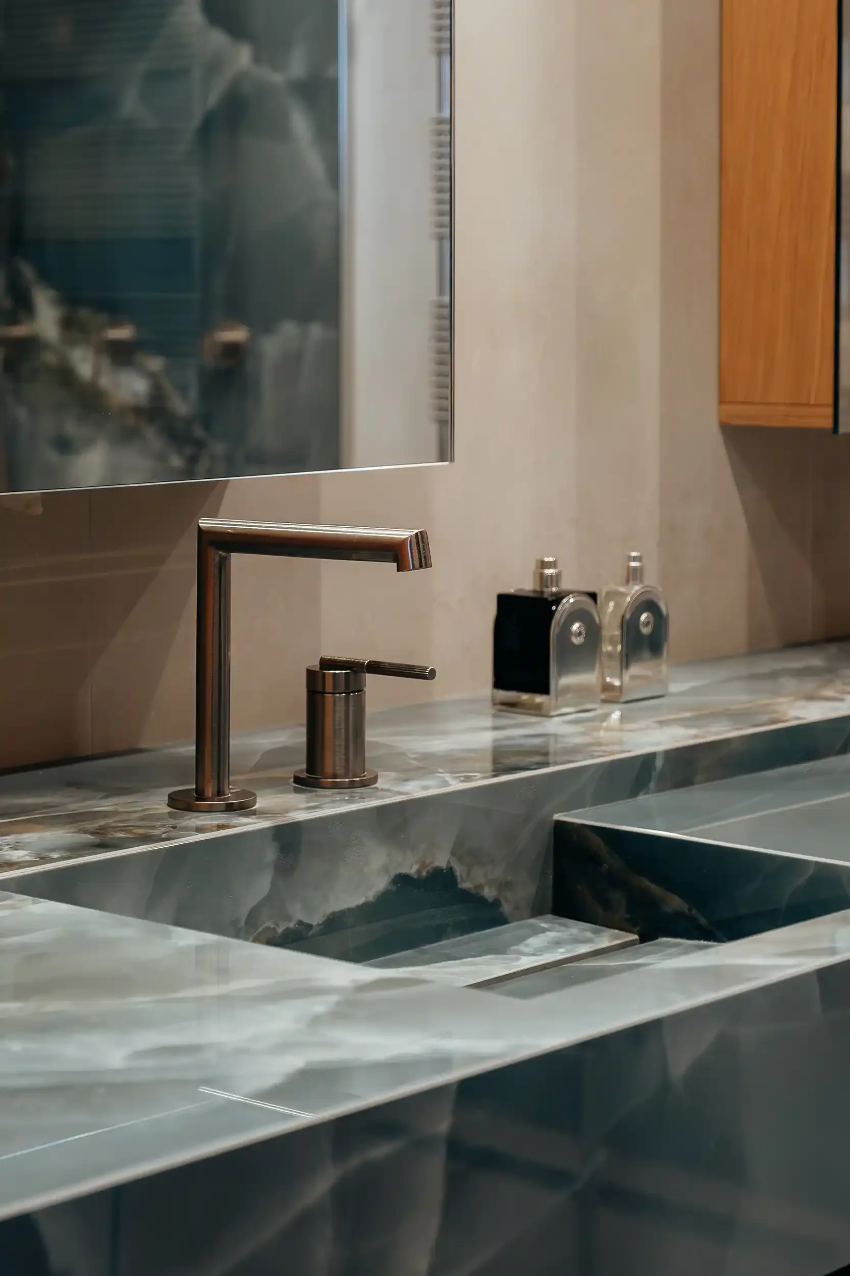 Détail d'un plan de toilette luxueux en onyx bleu avec vasque intégrée et mitigeur design en finition inox brossé.