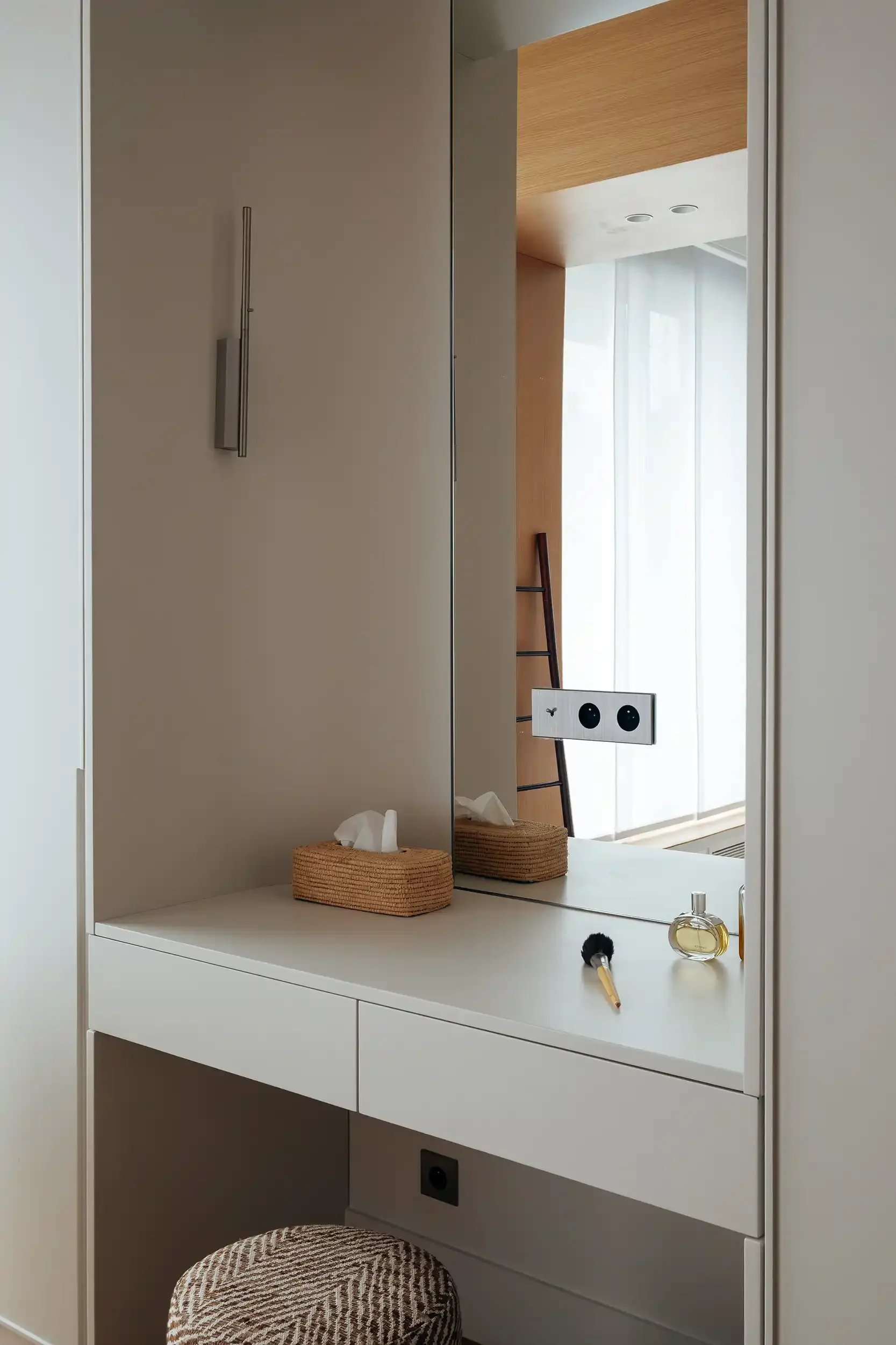 Détail d'un meuble coiffeuse blanc épuré avec tiroirs sans poignées, miroir et accessoires de beauté.