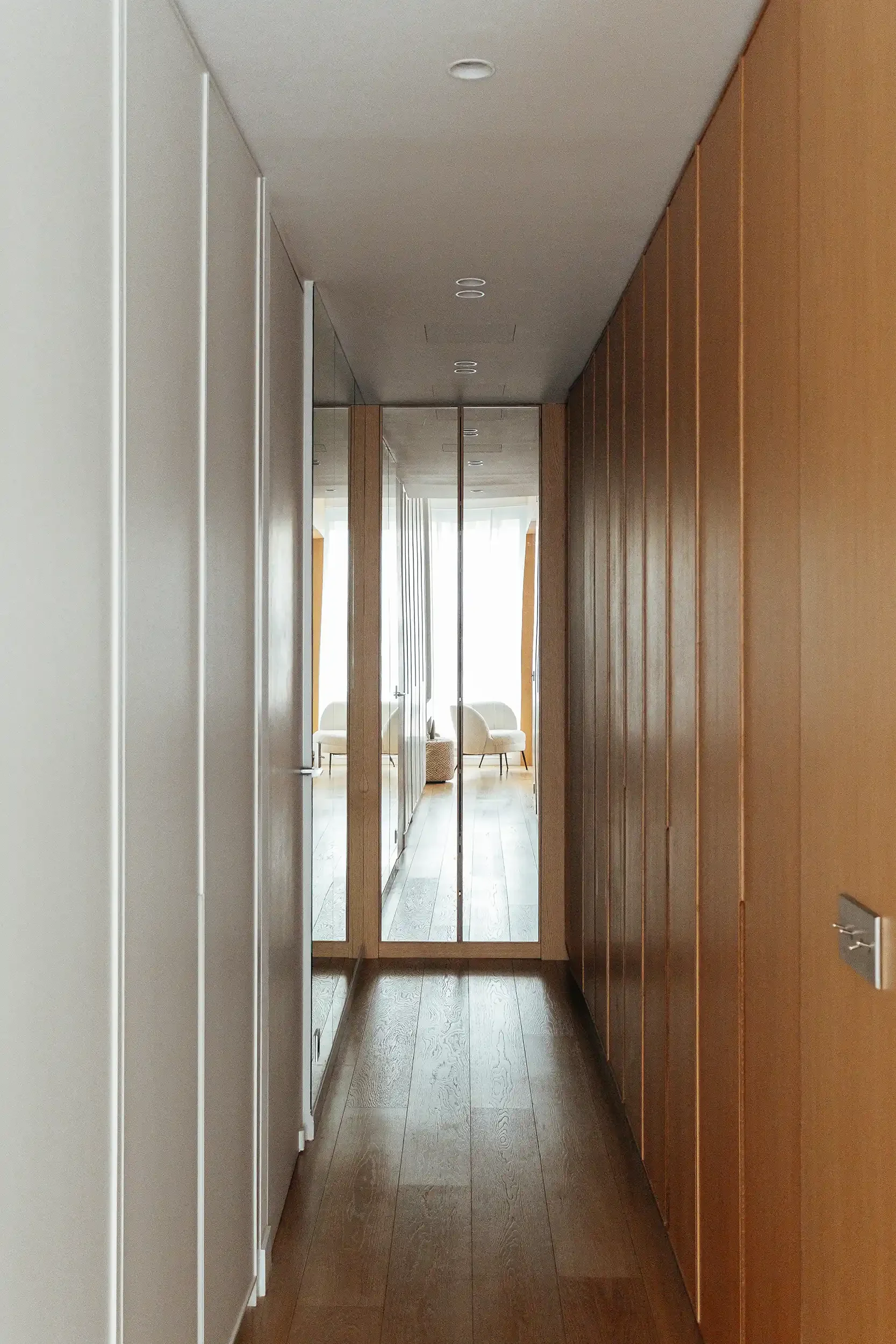 Couloir d'entrée minimaliste avec placards intégrés en bois clair et grand miroir toute hauteur pour agrandir l'espace.