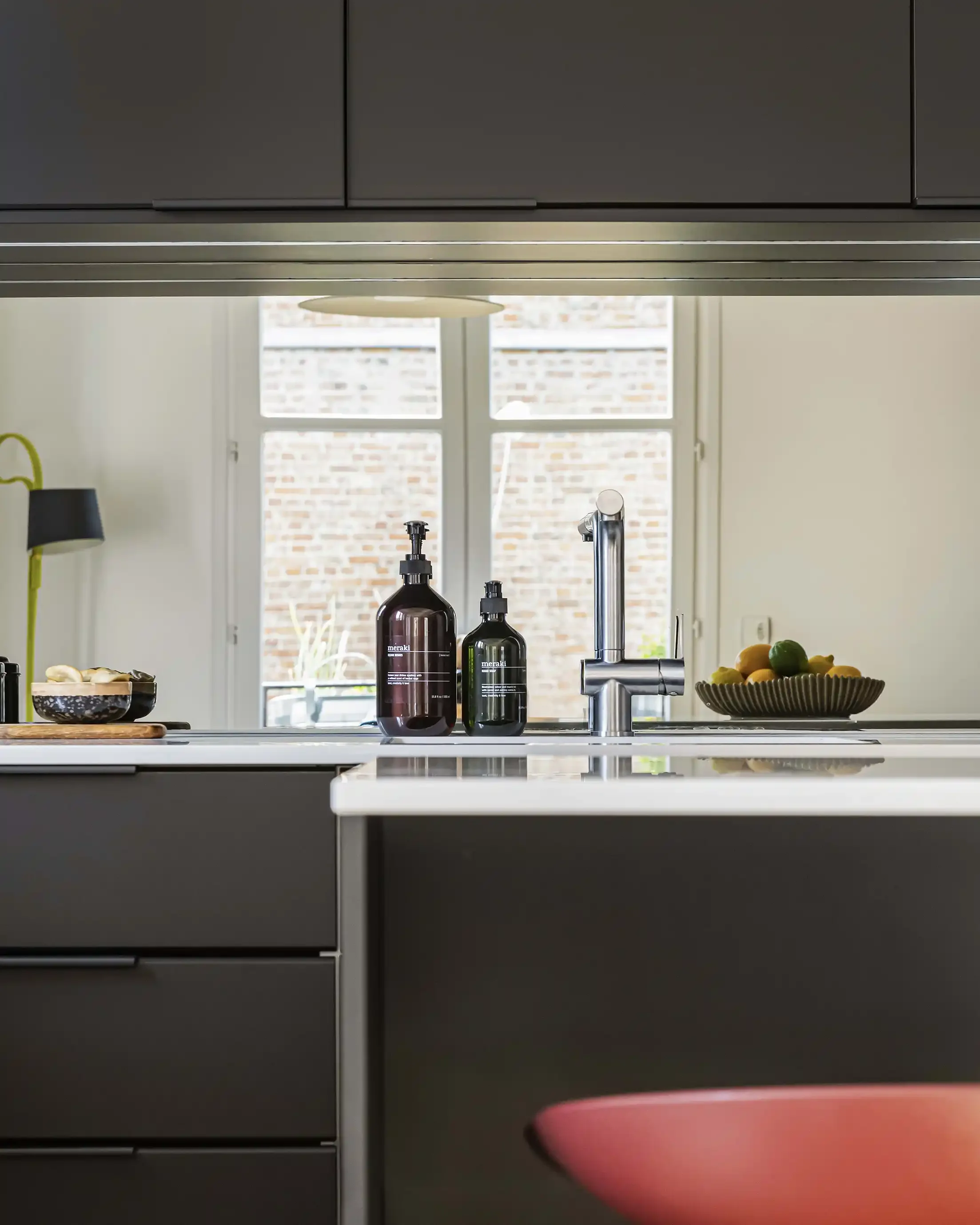 Détail du plan de travail blanc d'une cuisine noire avec évier sous plan et robinetterie en inox brossé.