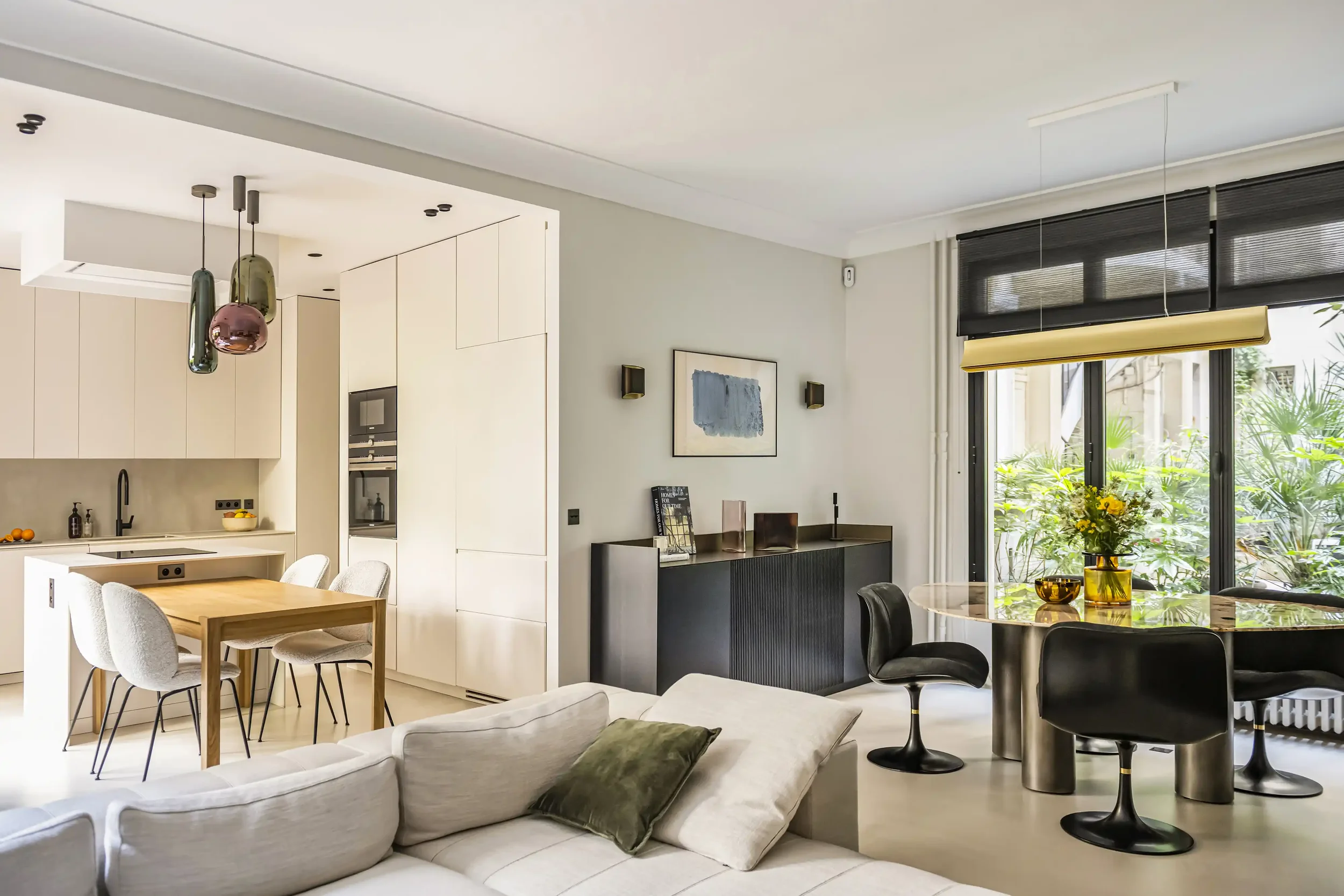 Rénovation d'un appartement à Paris : cuisine ouverte sur salon avec îlot central et table à manger en bois.