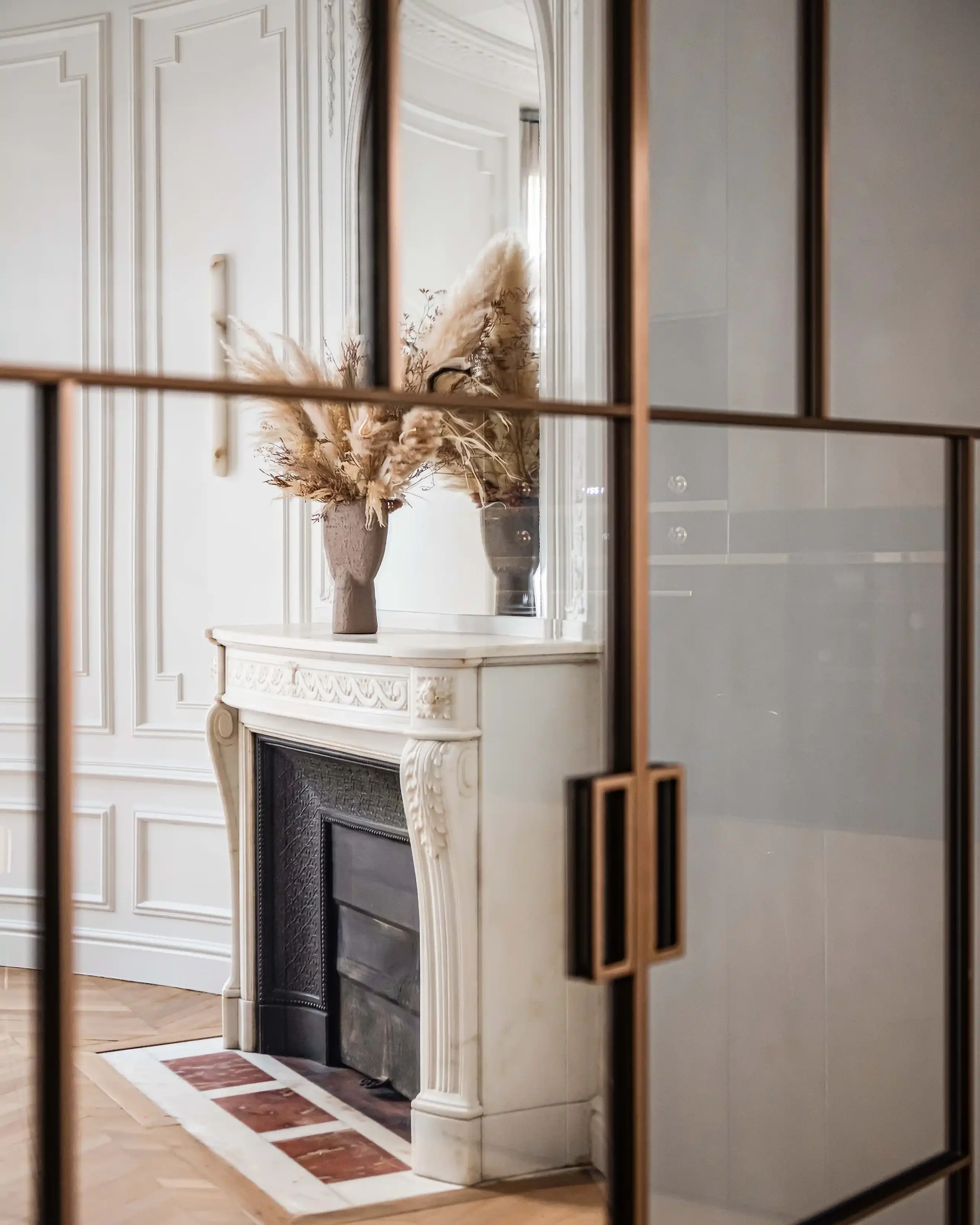 Vue en reflet d'une cheminée ancienne restaurée avec parquet en point de Hongrie et verrière de séparation.