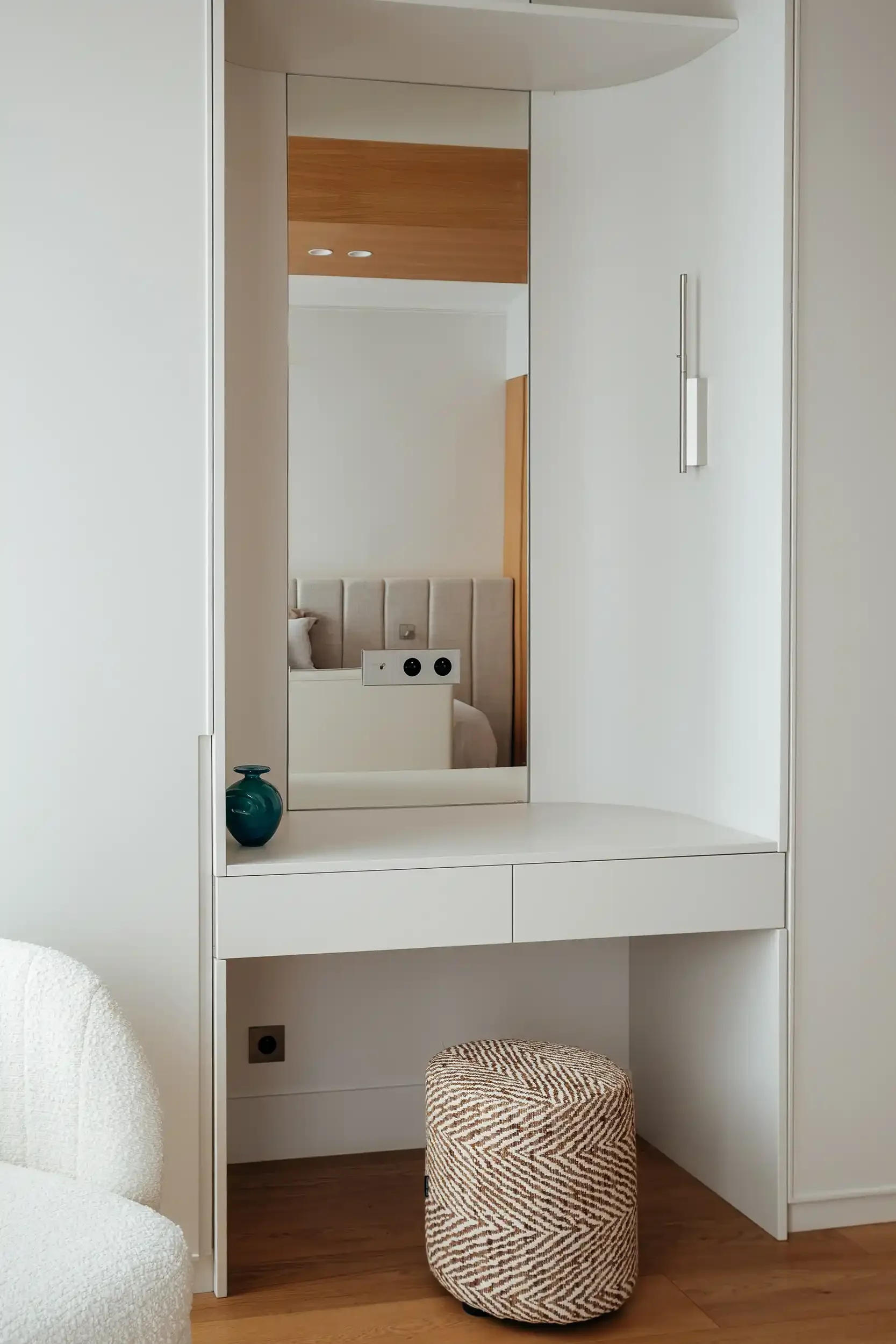 Coiffeuse moderne intégrée blanche avec grand miroir vertical, assise en tissu texturé et applique design minimaliste.