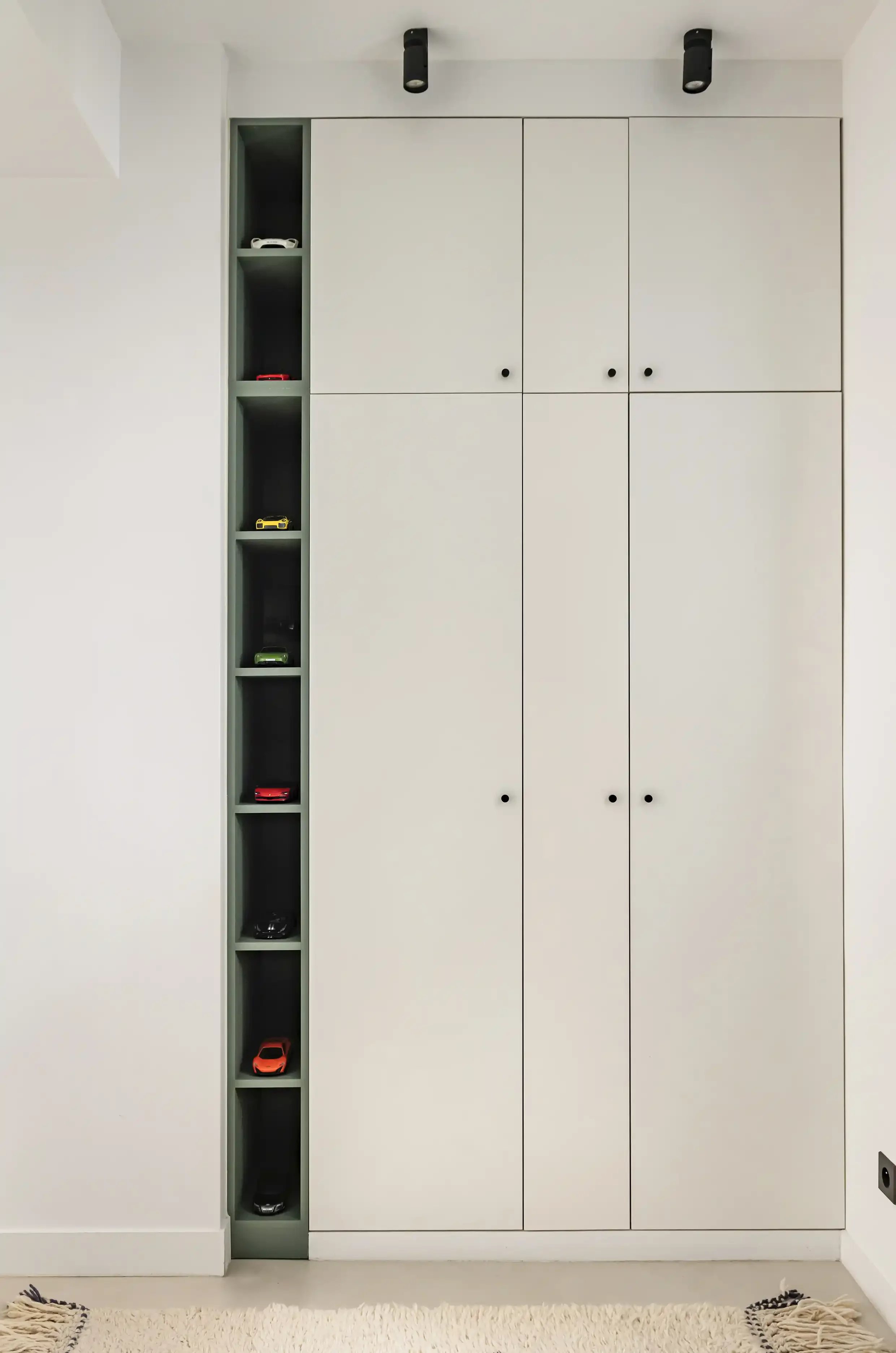 Rangement sur-mesure pour chambre d'enfant avec armoires encastrées beiges et niches vert forêt de décoration ouvertes.