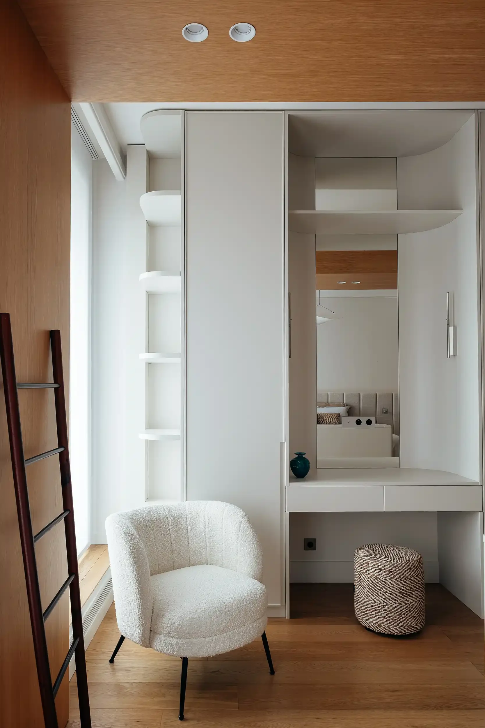 Coin coiffeuse sur mesure avec miroir toute hauteur, étagères rétroéclairées et fauteuil en bouclettes blanc dans une chambre moderne.