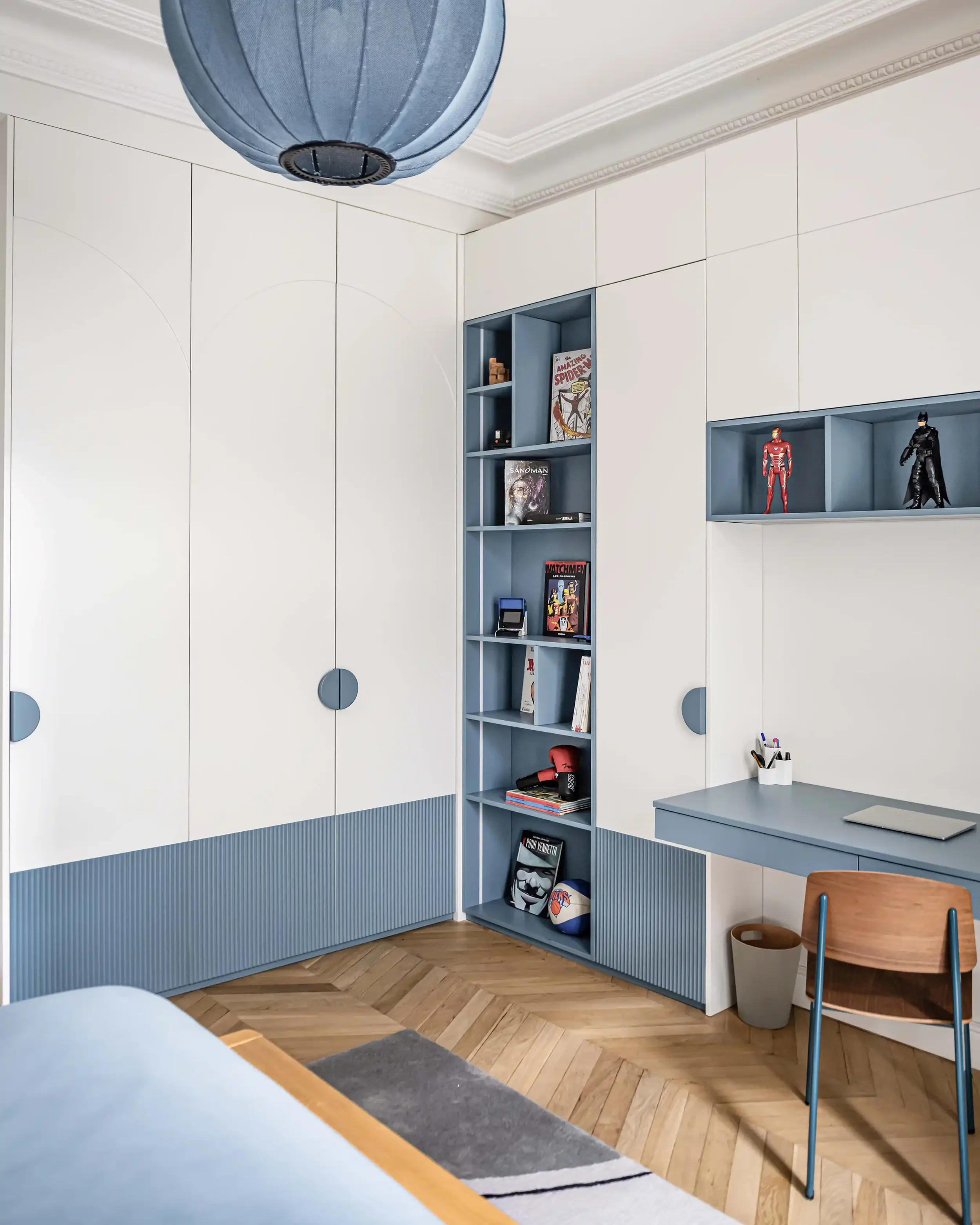 Chambre d'enfant avec bibliothèque et bureau intégrés sur mesure en bleu et blanc dans un appartement haussmannien.
