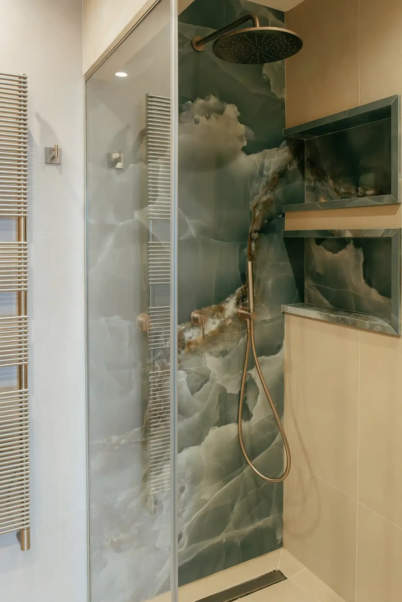 Salle de bain de luxe avec paroi de douche en onyx bleu, niches de rangement rétroéclairées et colonne de douche en laiton.
