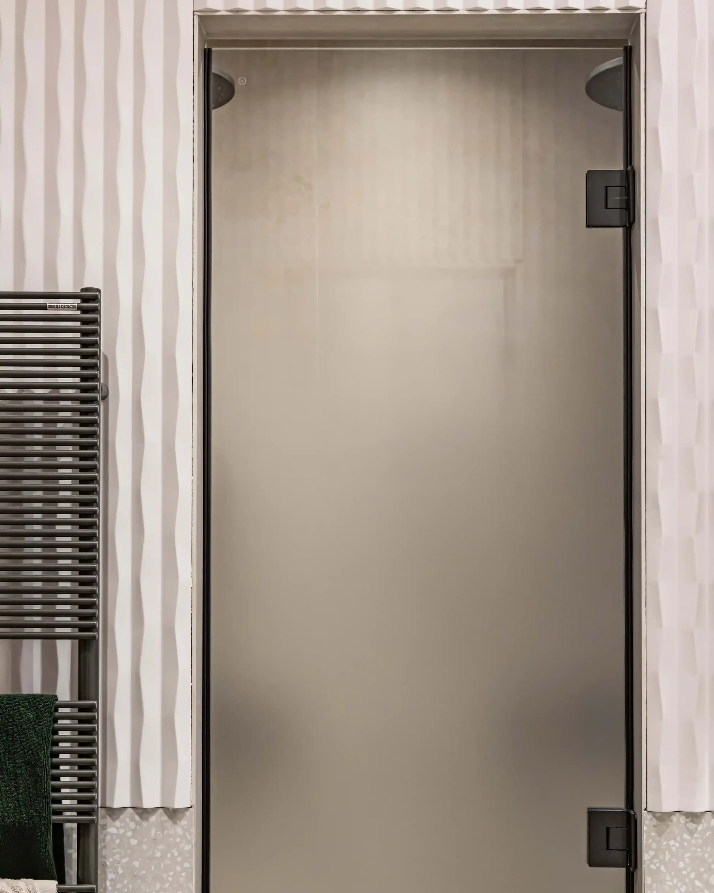 Salle de bain élégante avec douche à l'italienne, paroi en verre dépoli et robinetterie noire minimaliste.
